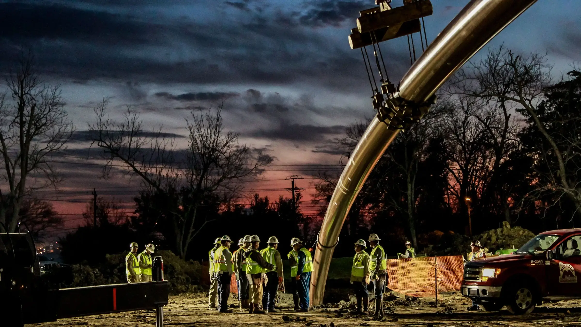 Many crew members stand around a pipe entering the ground