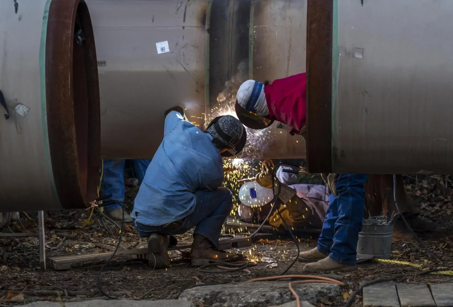 Employees welding two pipes with sparks flying