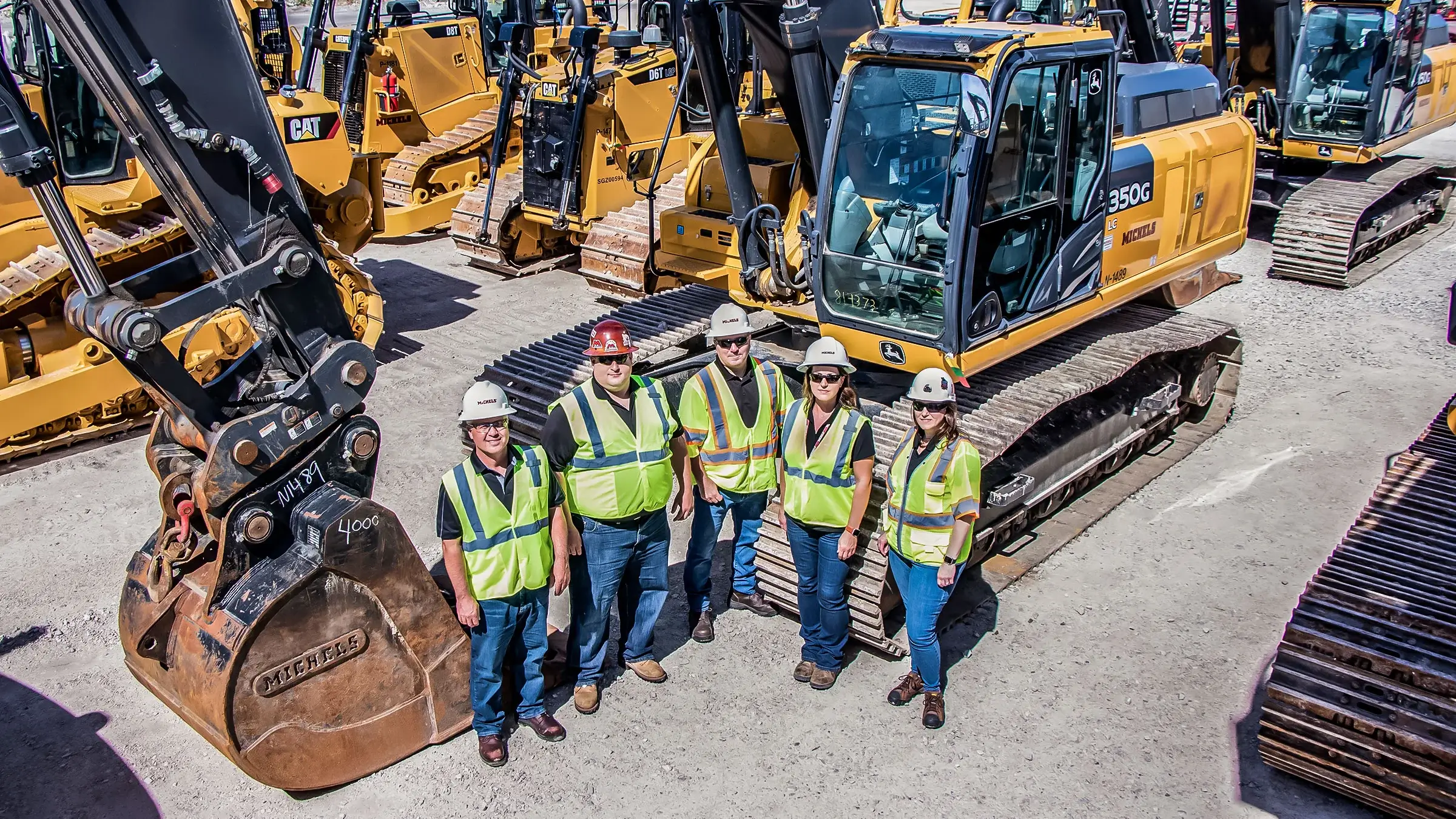 Five people stand in front of construction equipment