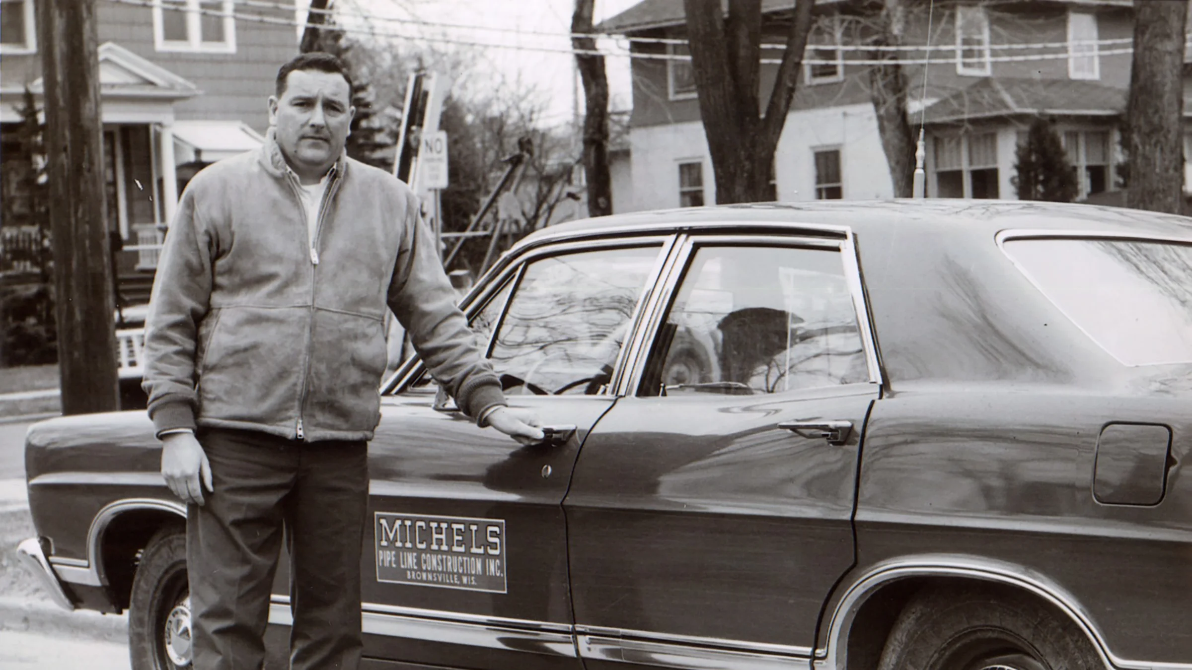 Dale Michels stands next to a car in an archival photo