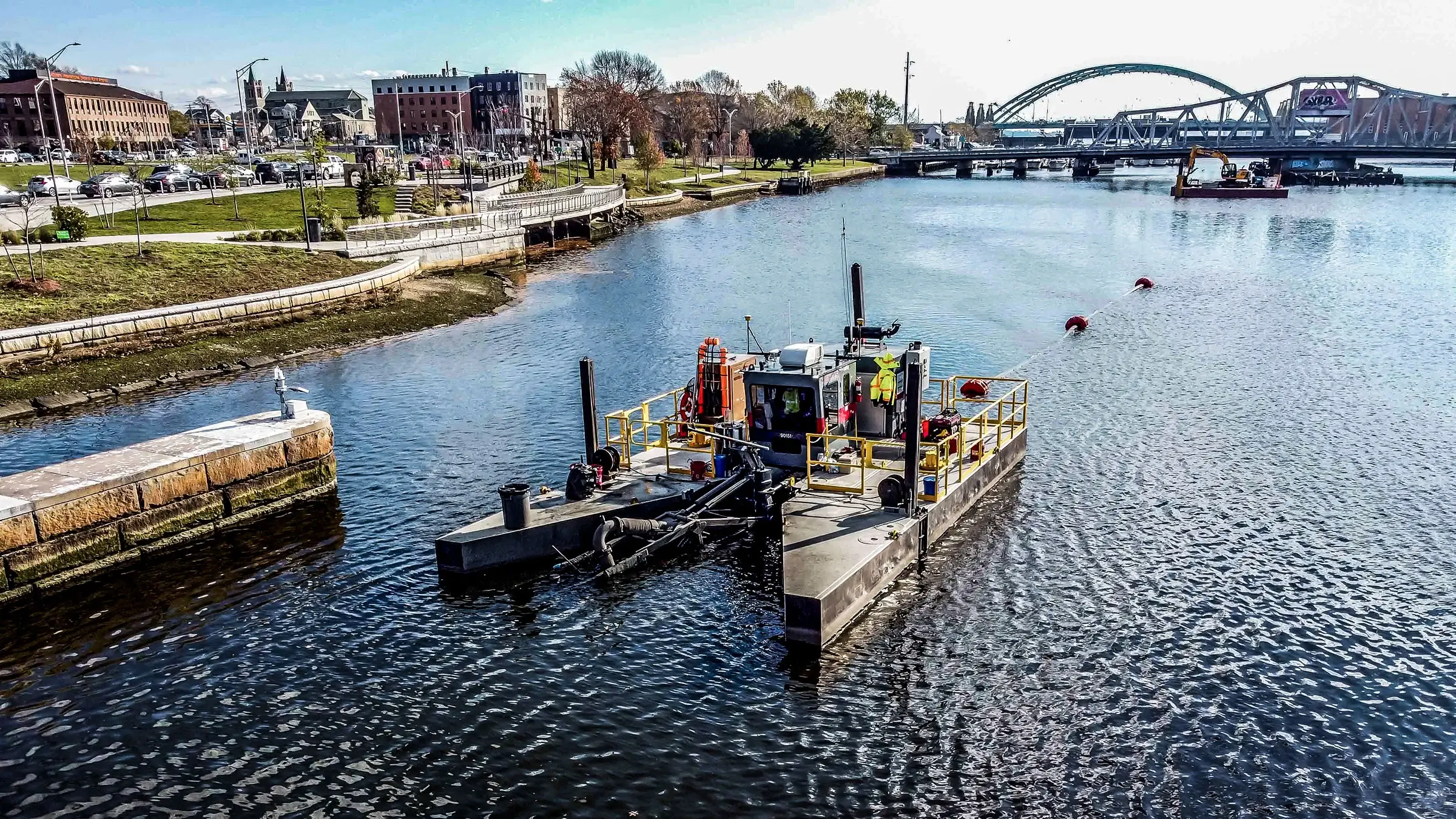 A dredging vessel operates on a city riverway