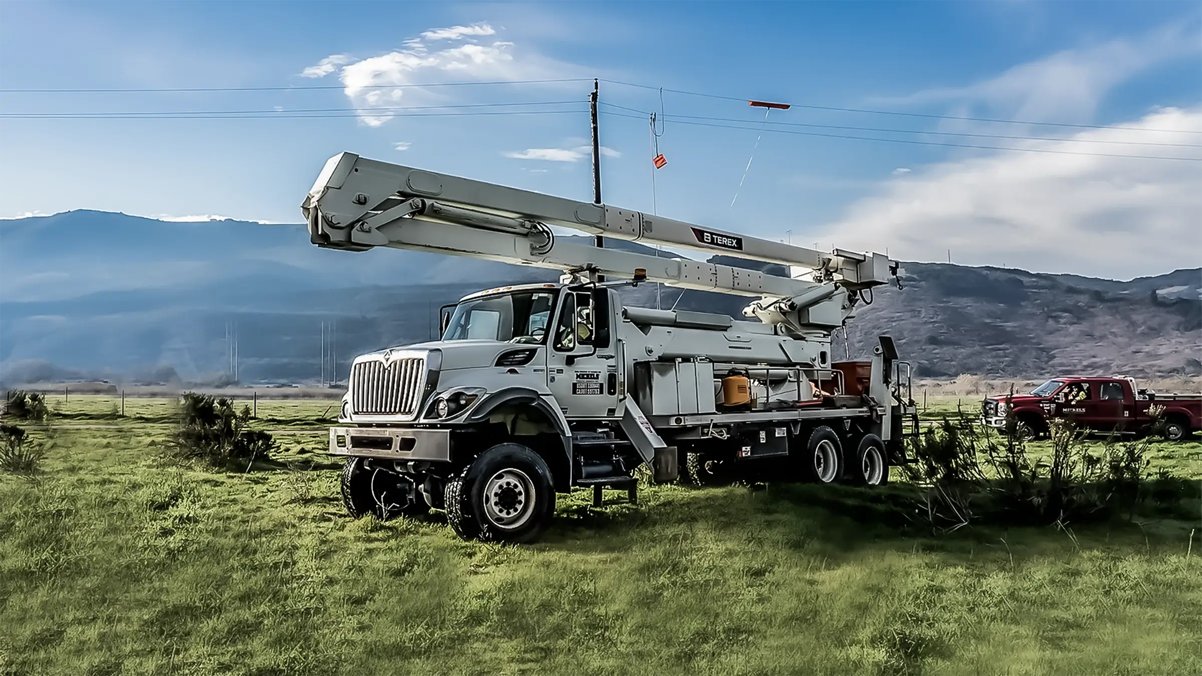 A Michels Pacfic Energy bucket truck is parked in a field on a sunny day