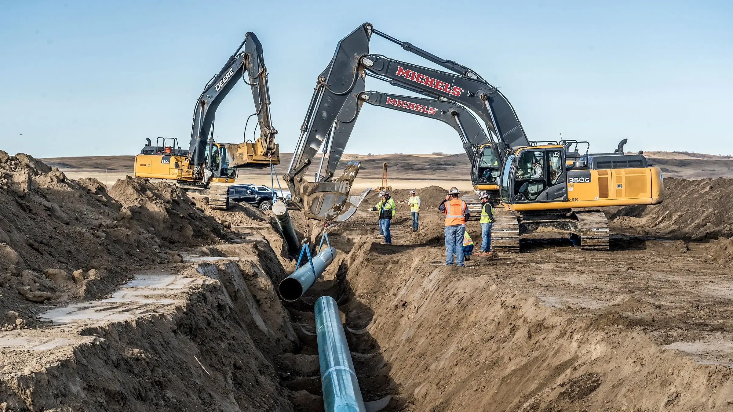 Excavators install pipeline in trench