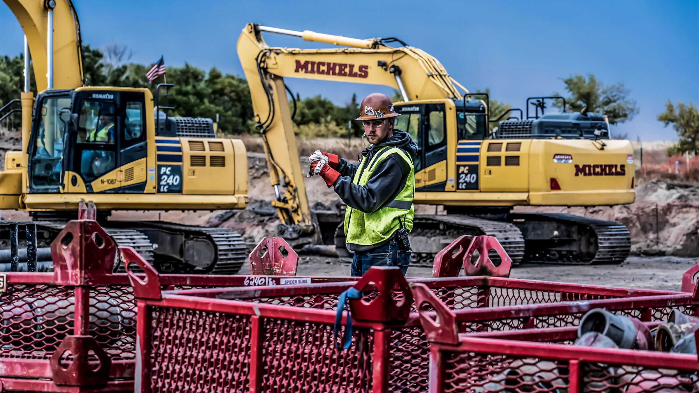 A field worker uses hand signals to guide an operator on safe placement of a load