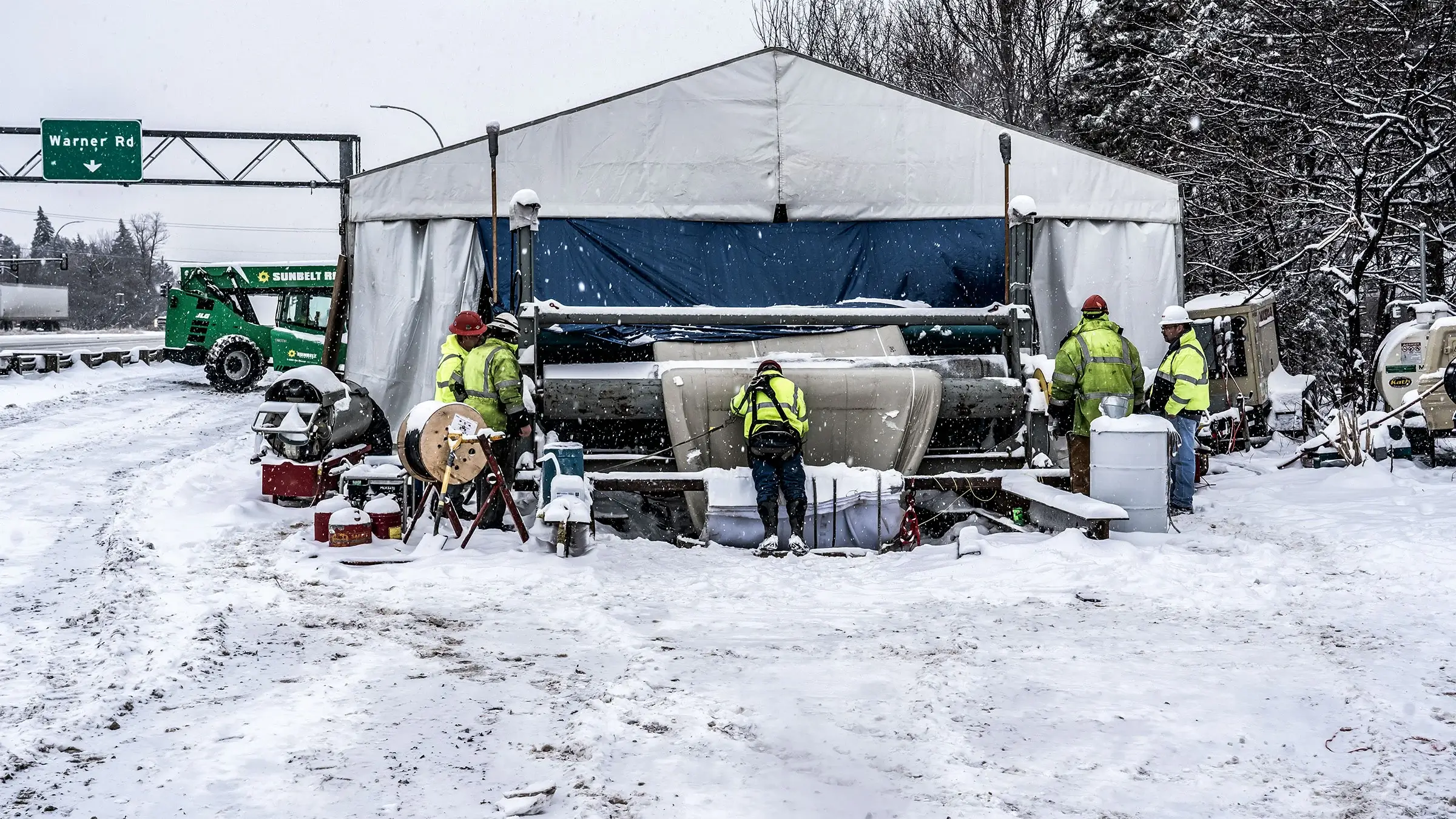 A large diameter CIPP liner is lowered into a sewer line from an over-the-hole setup