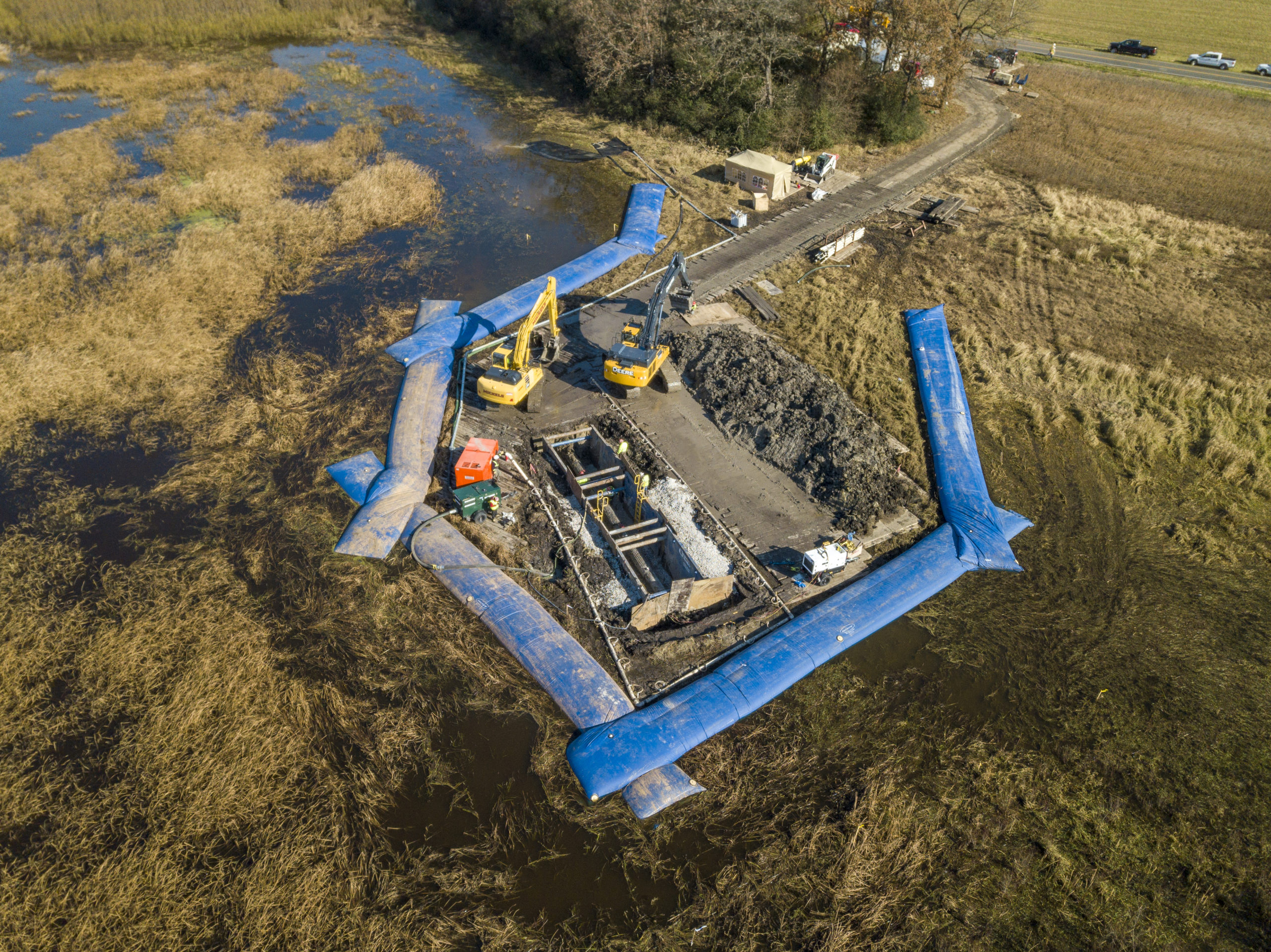 Large barriers protect crew as they work to recoat pipeline