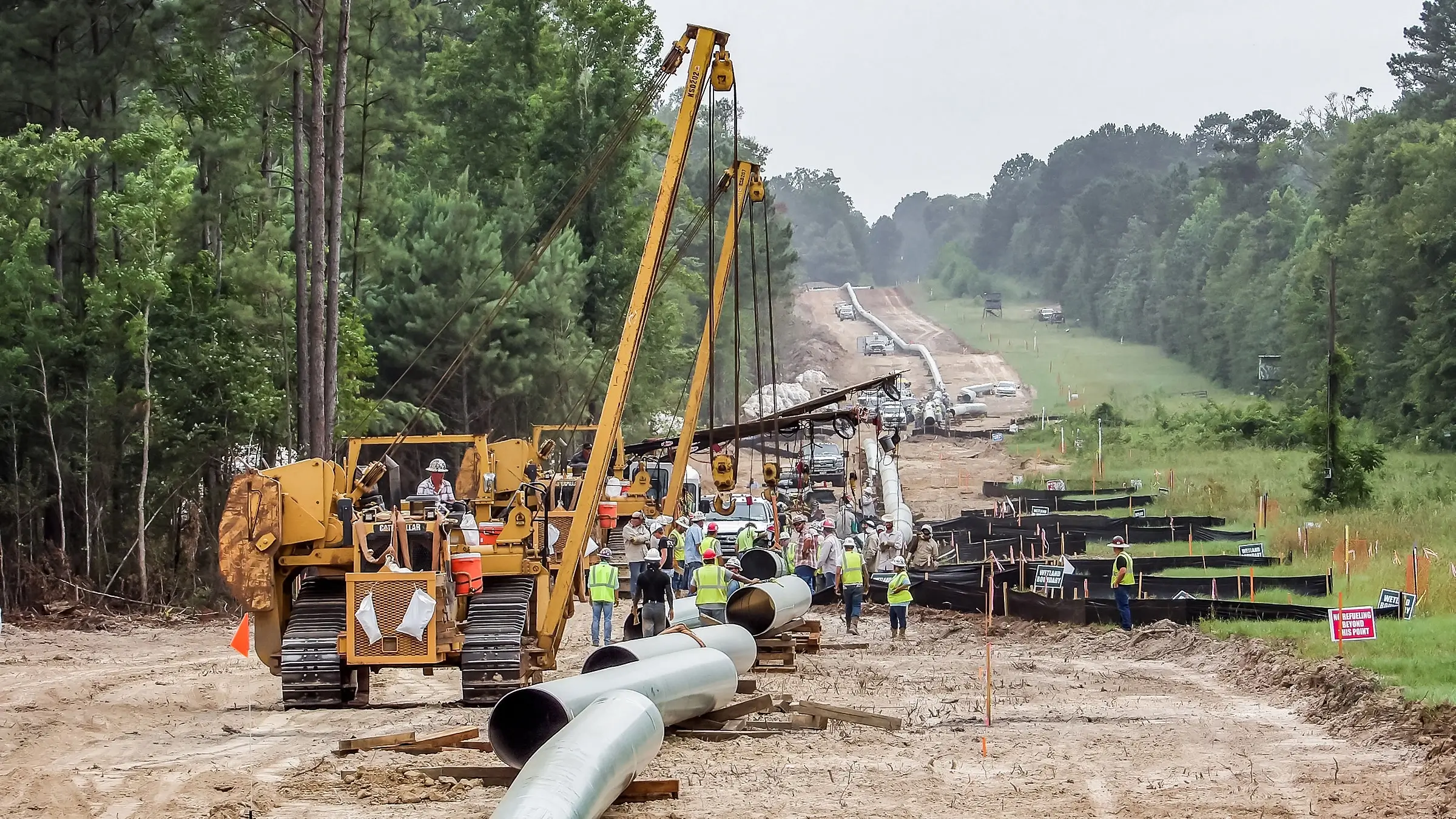 Multiple sidebooms carry separate sections of pipeline into place on a large project