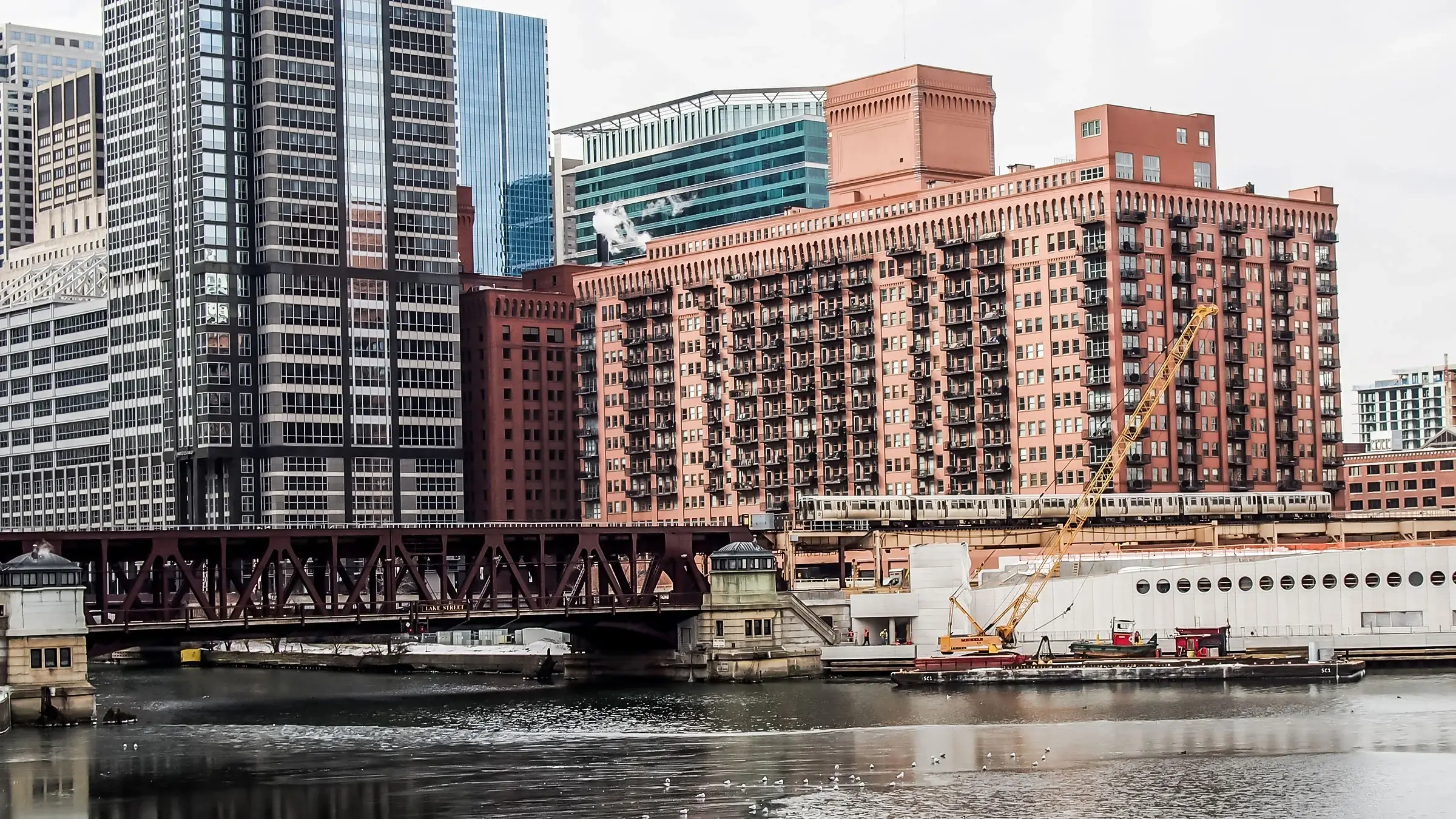 Michels working under an active bridge structure on a river.