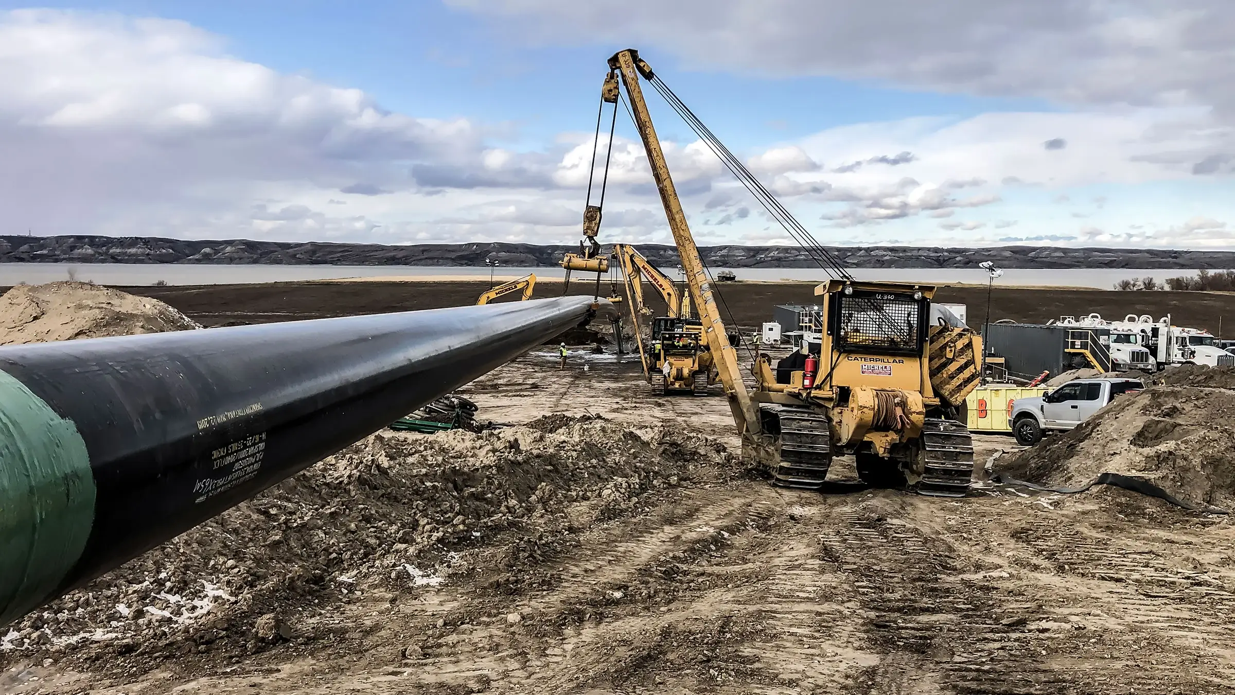 A pipelayer machine assists in supporting a large diameter pipeline near the Missouri River.