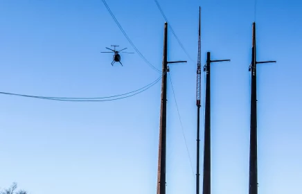 Helicopter flies over power poles and lines to check on them