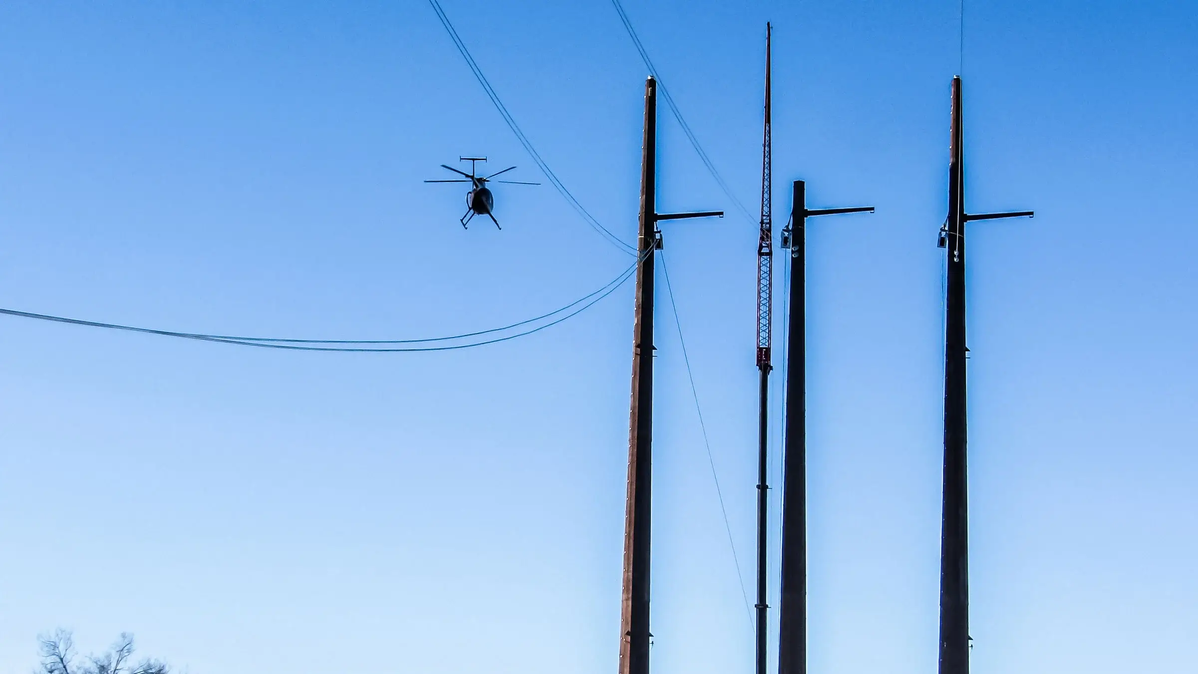 Helicopter flies over power poles and lines to check on them