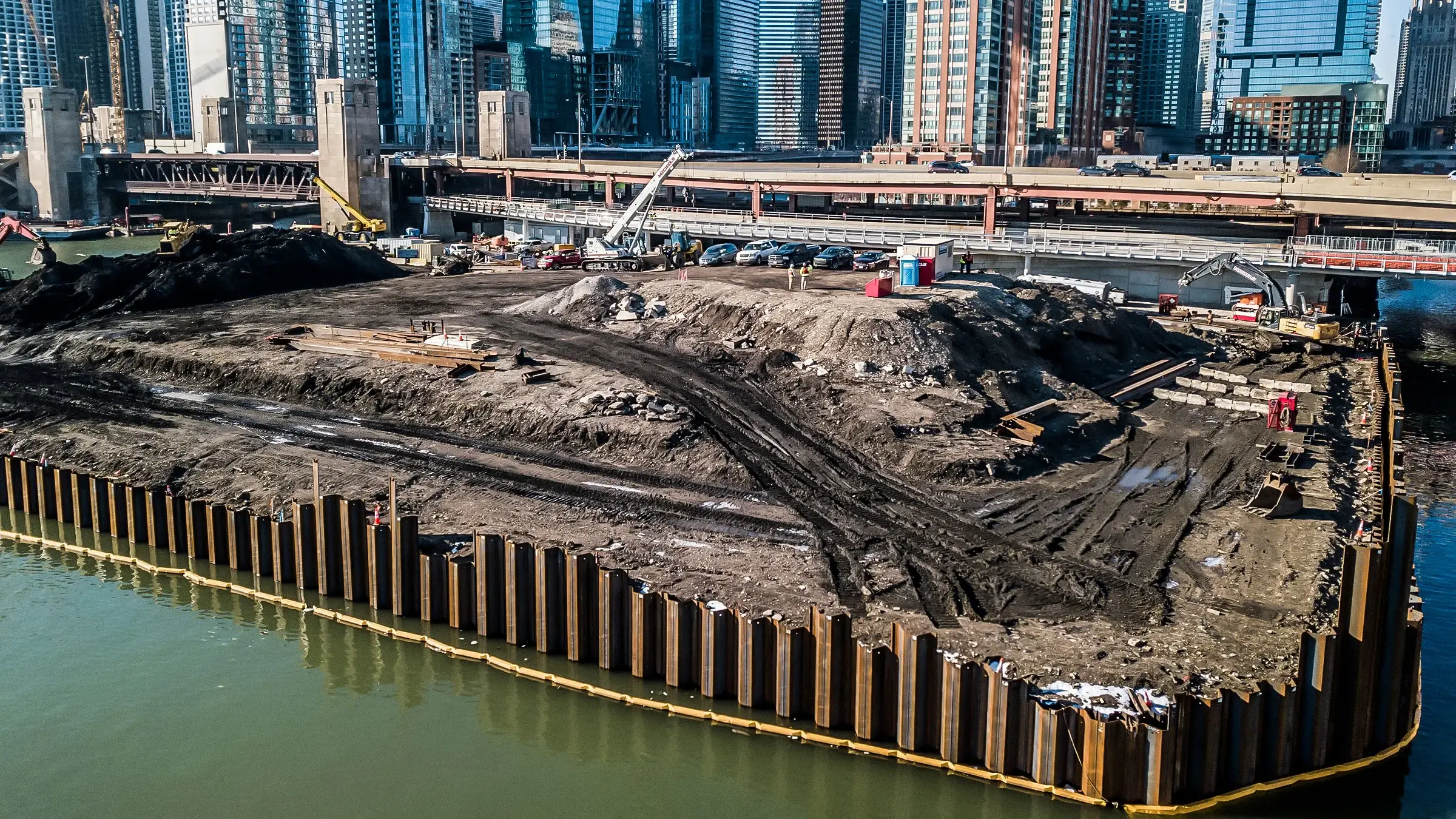 Mulitple excavators and backhoes operate near a seawall installation on the Chicago Lake Michigan waterfront