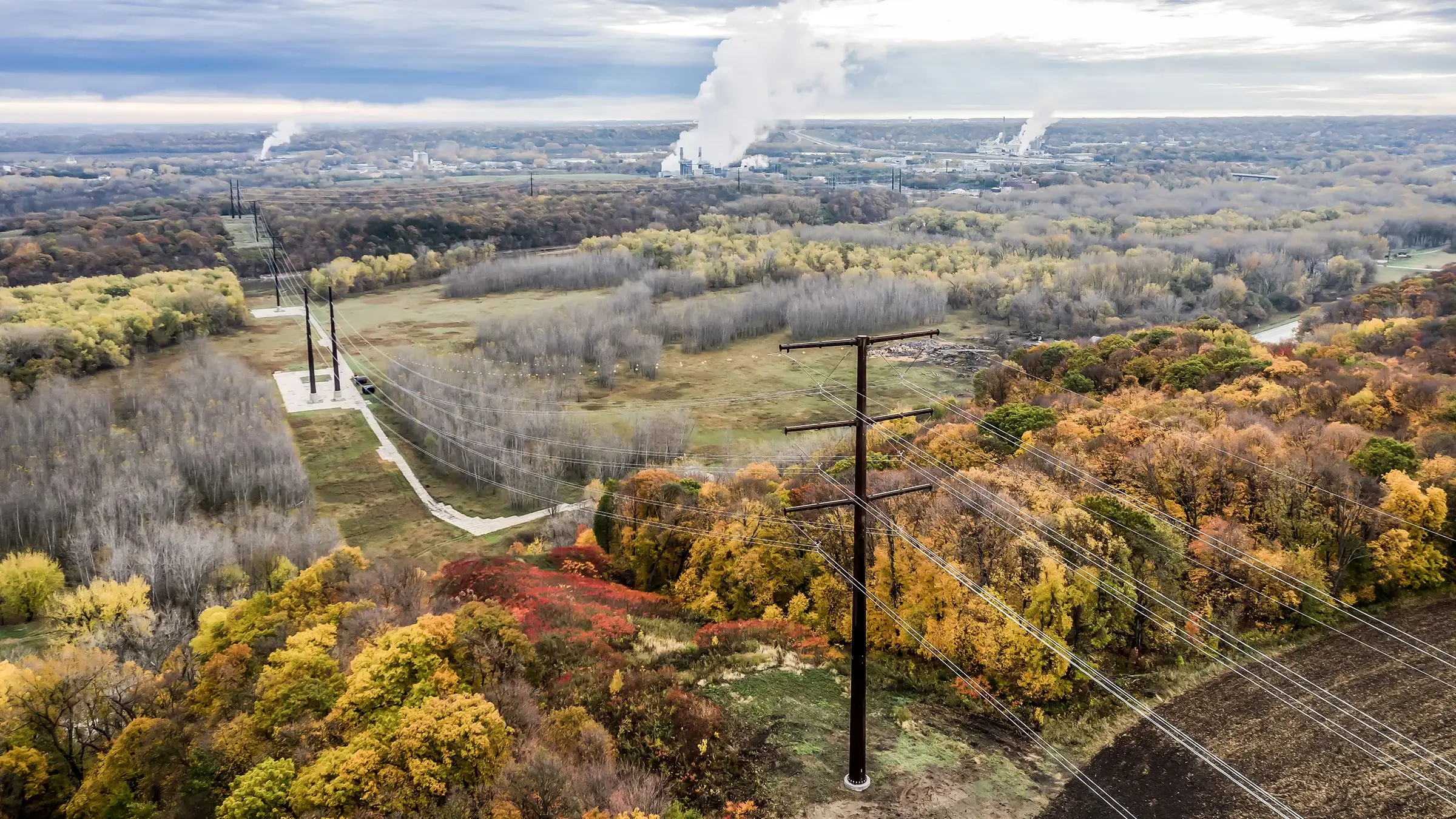 Main power line featured against a hillside with leaves changing colors for fall