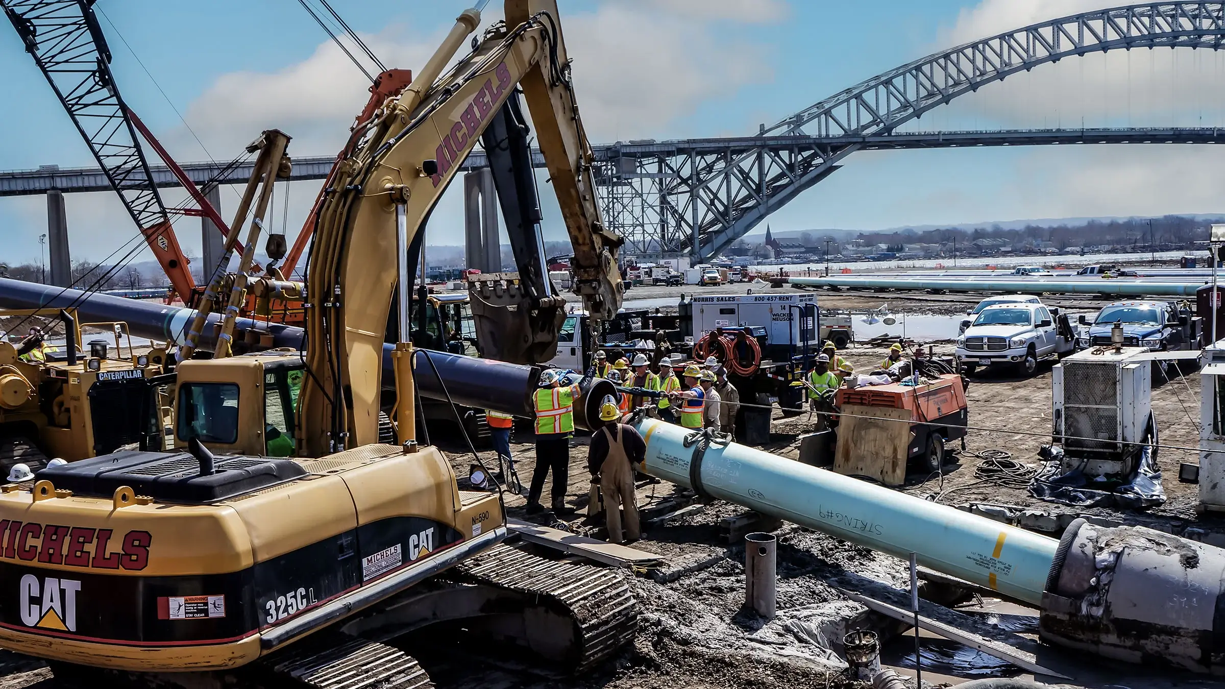 A Michels crew operates on a large diameter pipeline near a river.