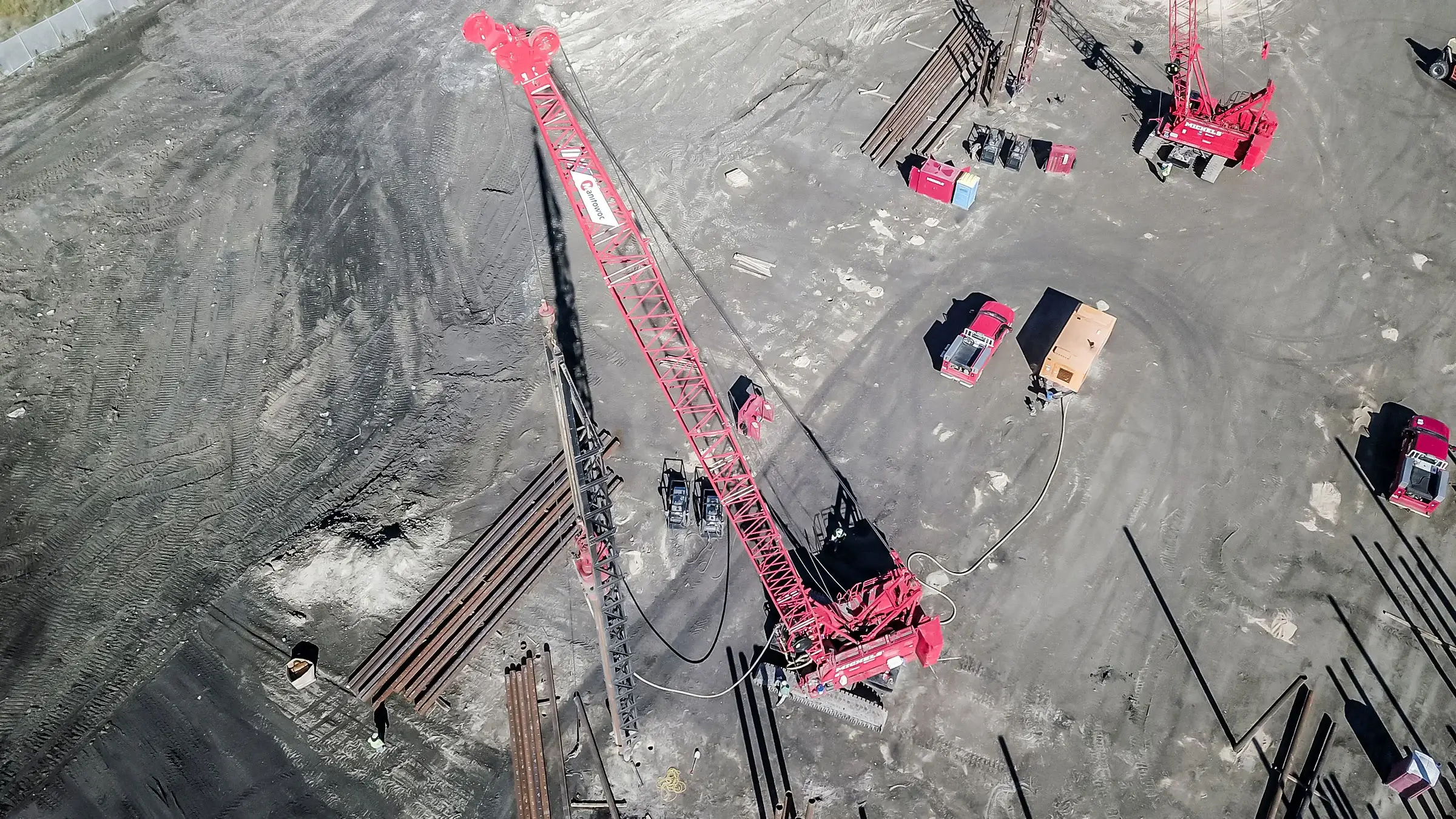 Two large red cranes install foundation pieces