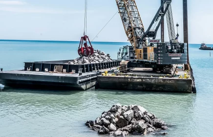 A crane lifts heavy aggregates off-shore from a barge in Lake Michigan