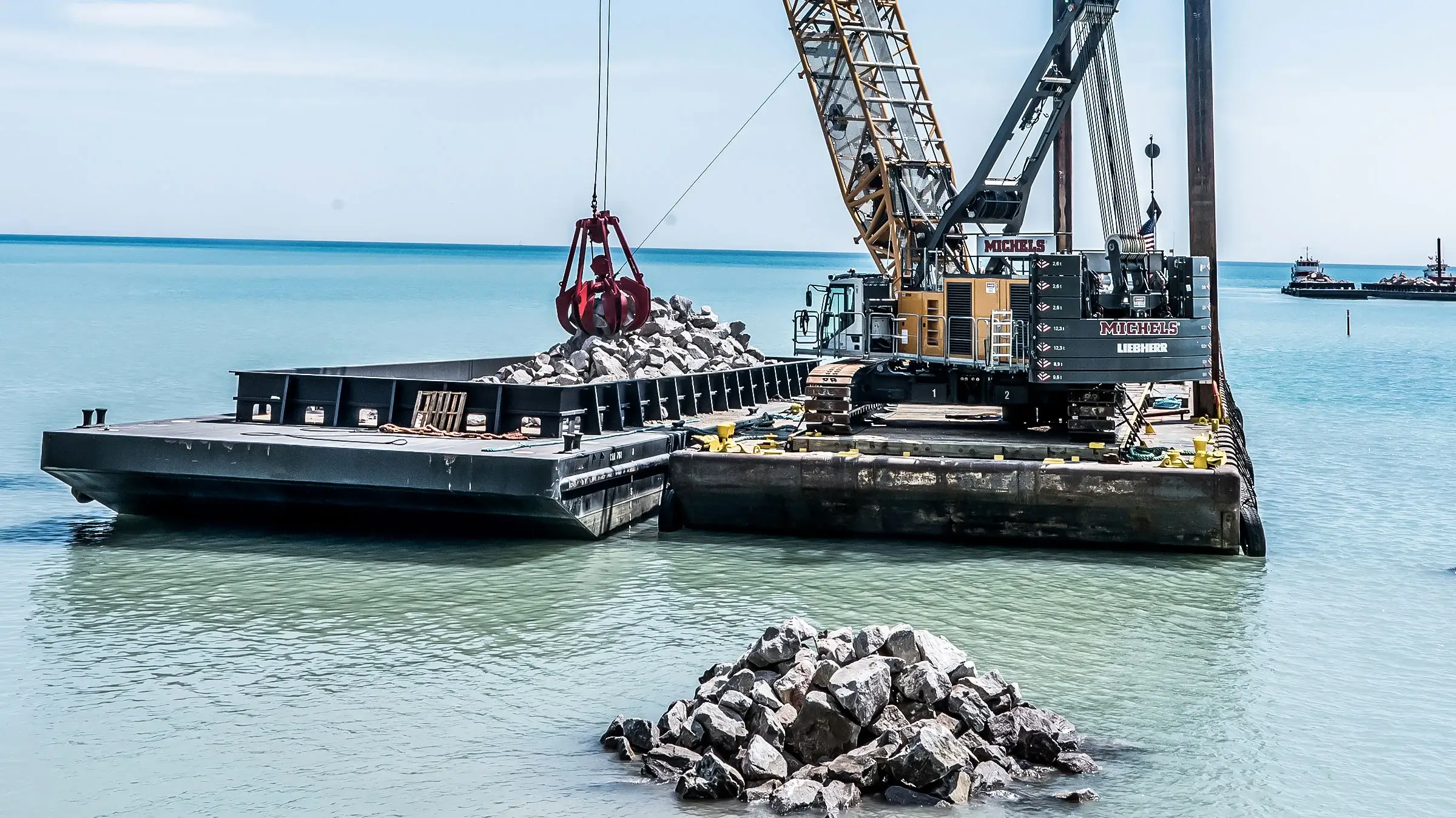 A crane lifts heavy aggregates off-shore from a barge in Lake Michigan