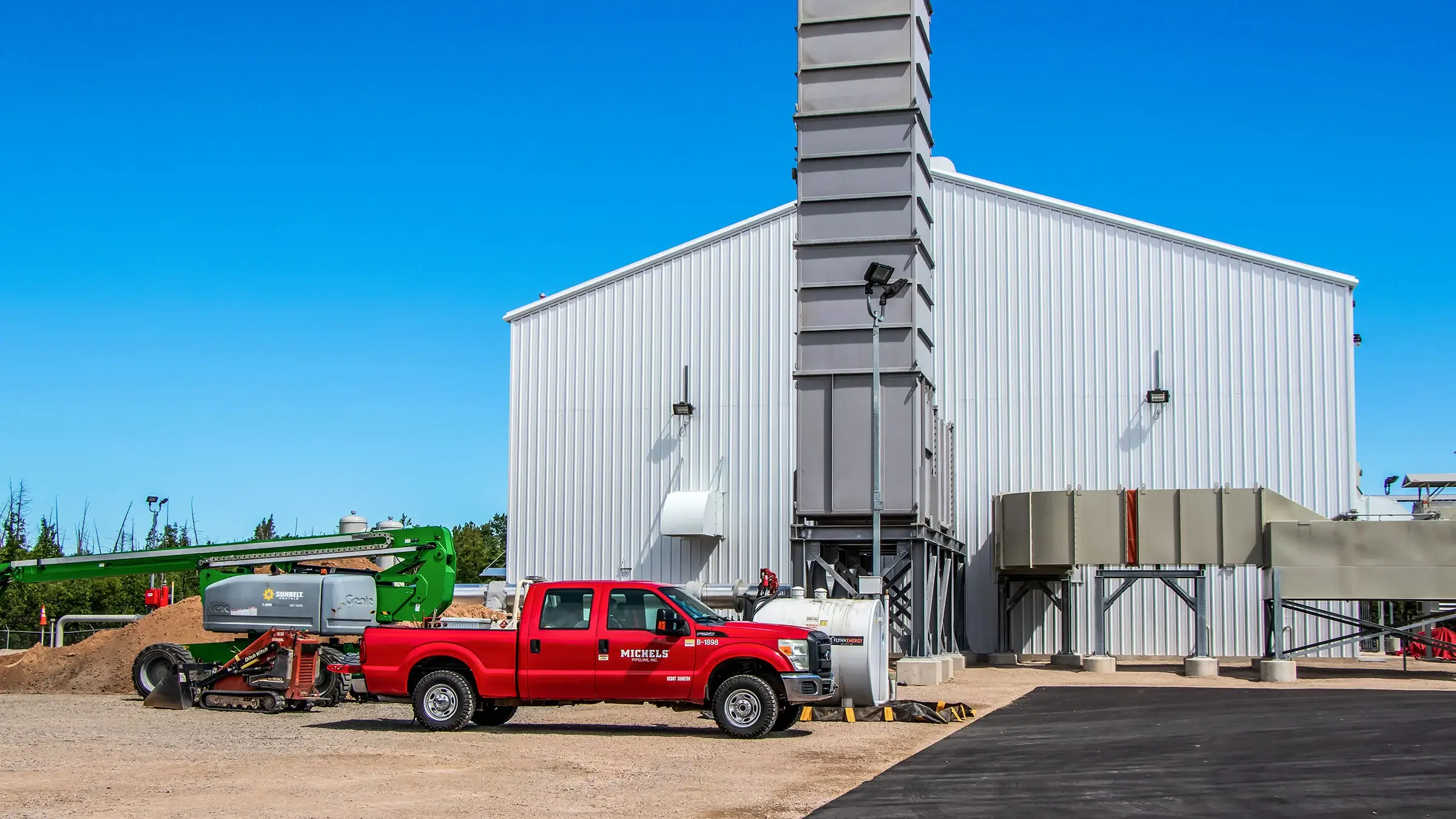 A red Michels truck sits outside of a compressor station facility.