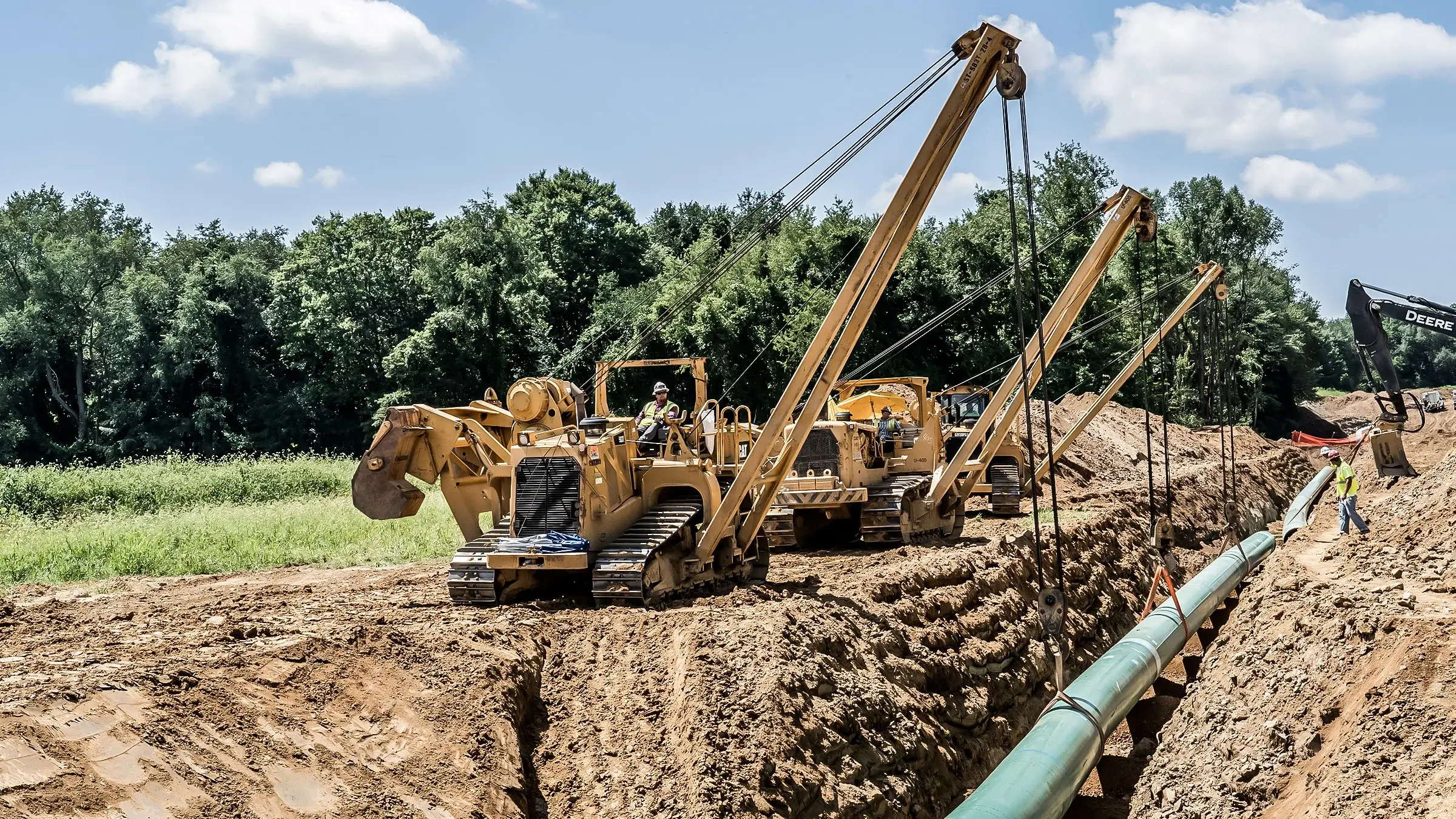 Crew operating sidebooms adjust pipeline in trench on Nexus project