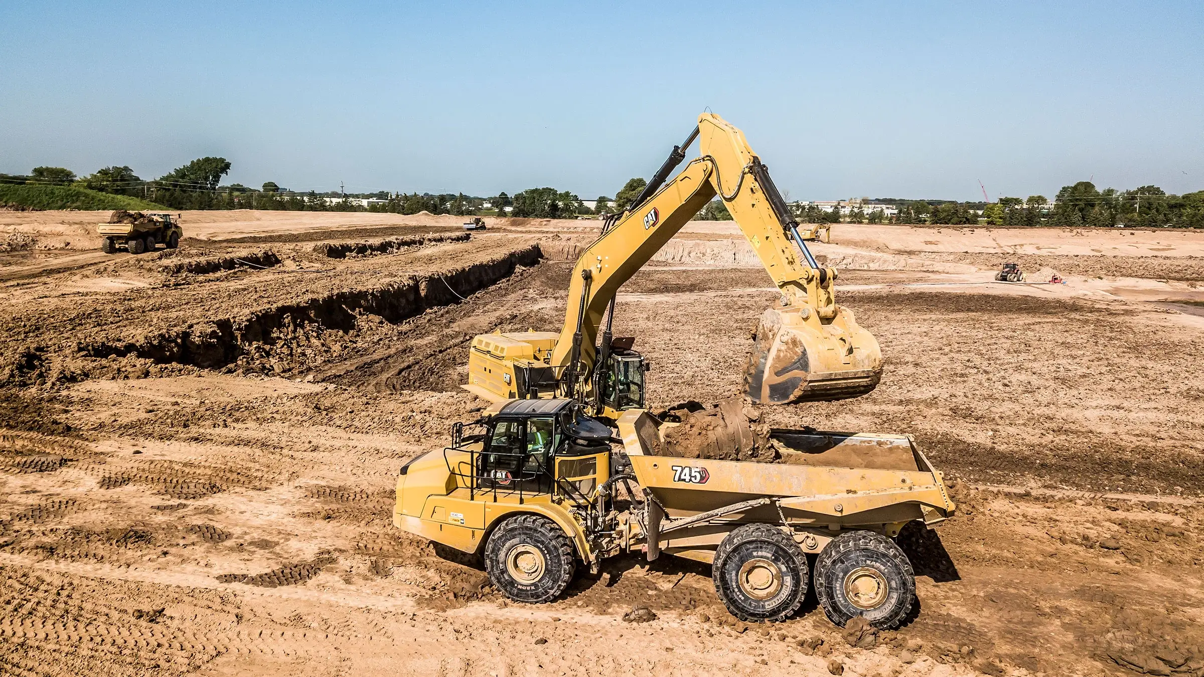 An excavator dumps dirt into a dump truck at a landfill