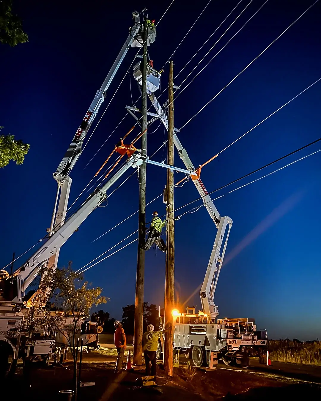 Crews from Michels Power, Inc. working on power lines at night.