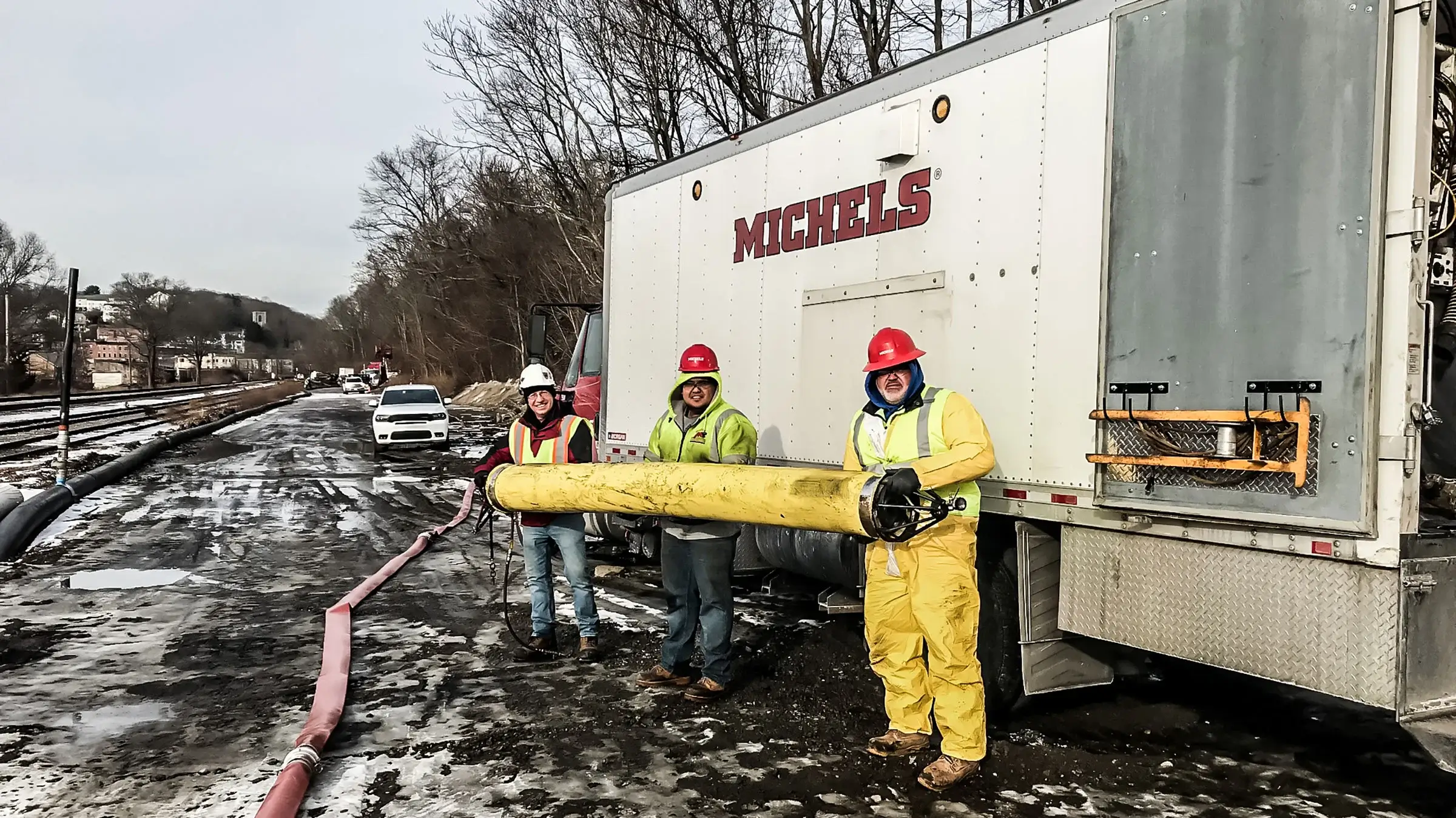 Three Michels crew members hold a portion of rehab pipe
