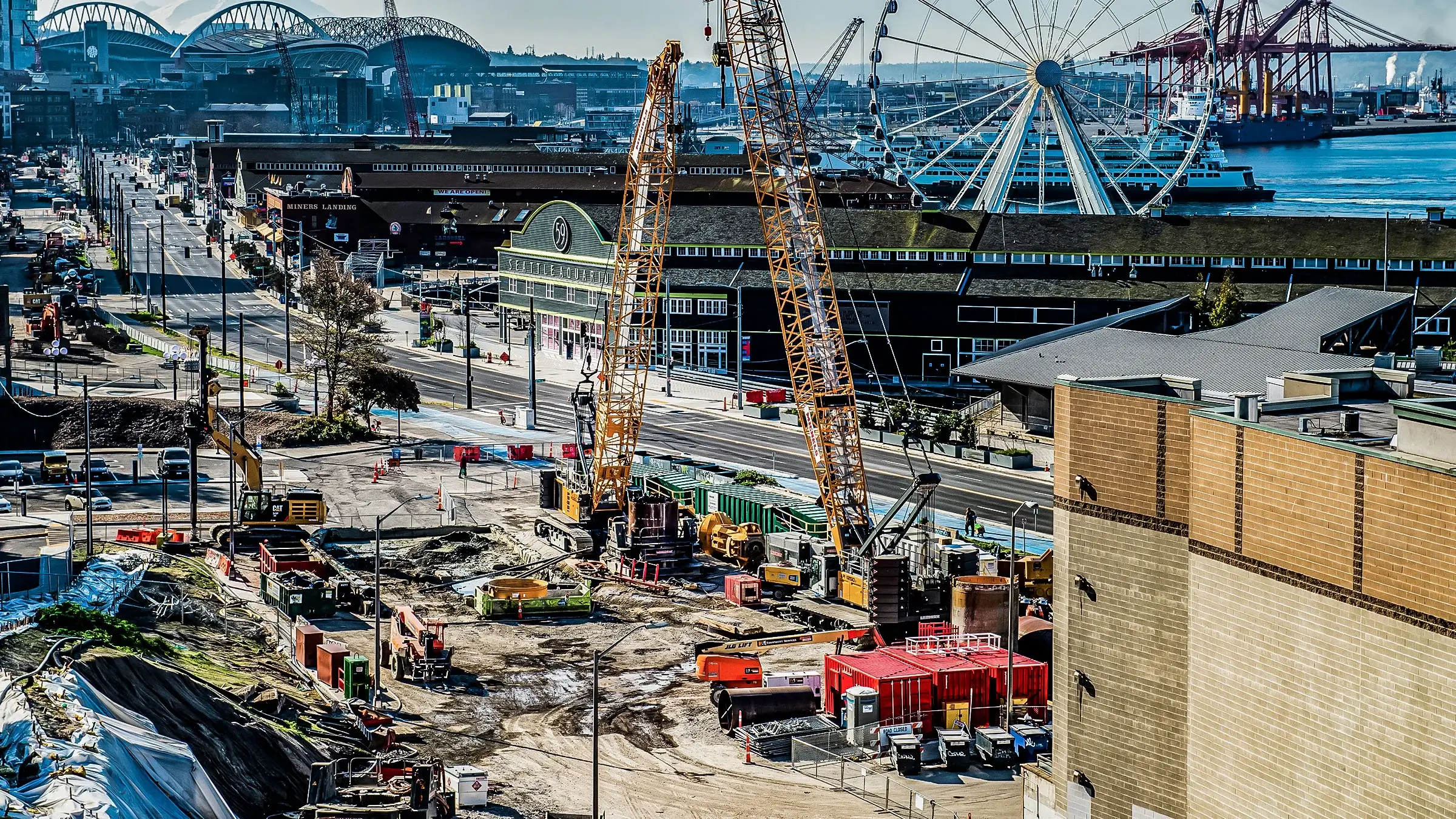 Two large cranes operate near the Seattle Waterfront on a foundations job