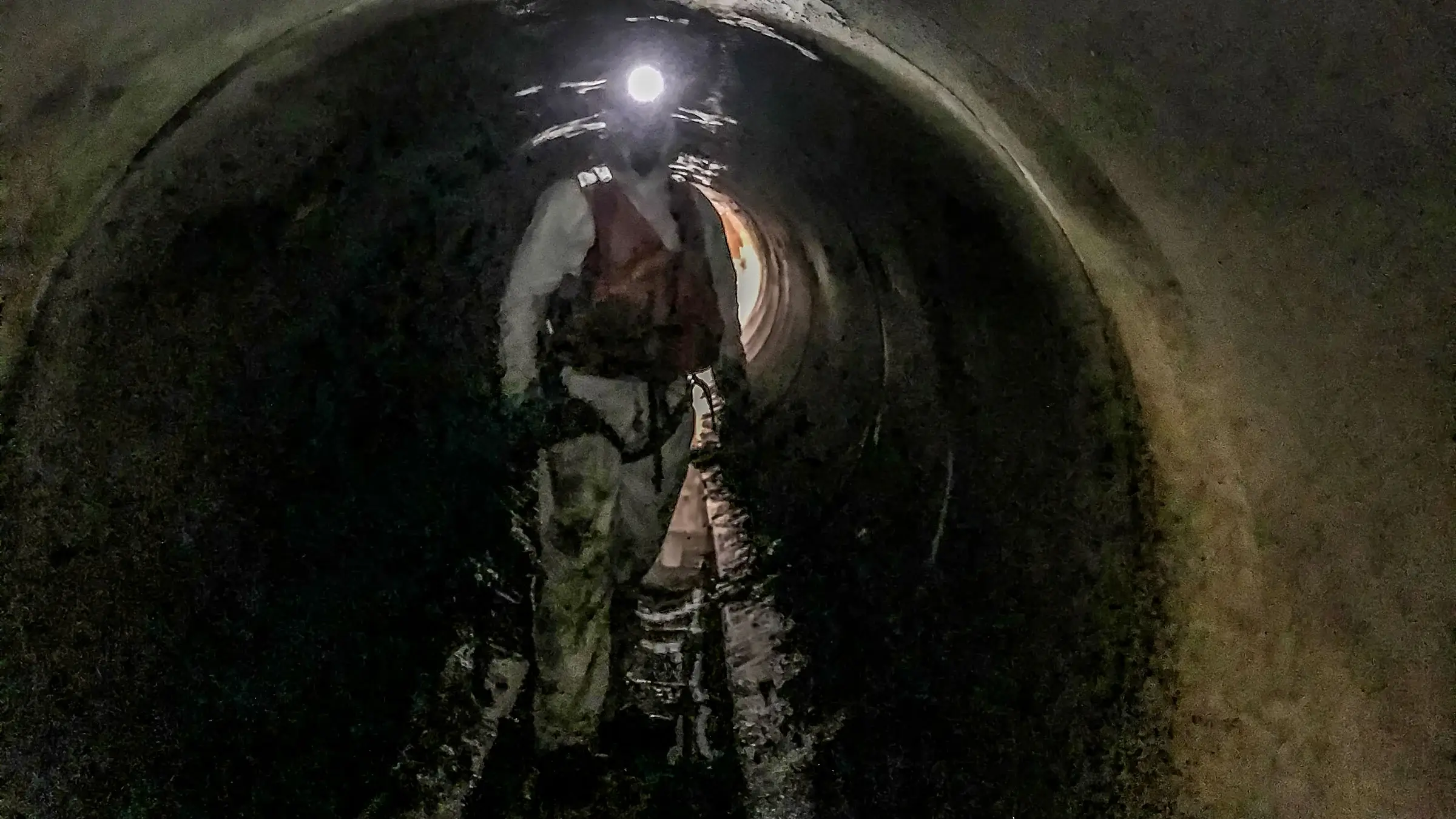 A crew member walks on the inside of an underground sewer tunnel
