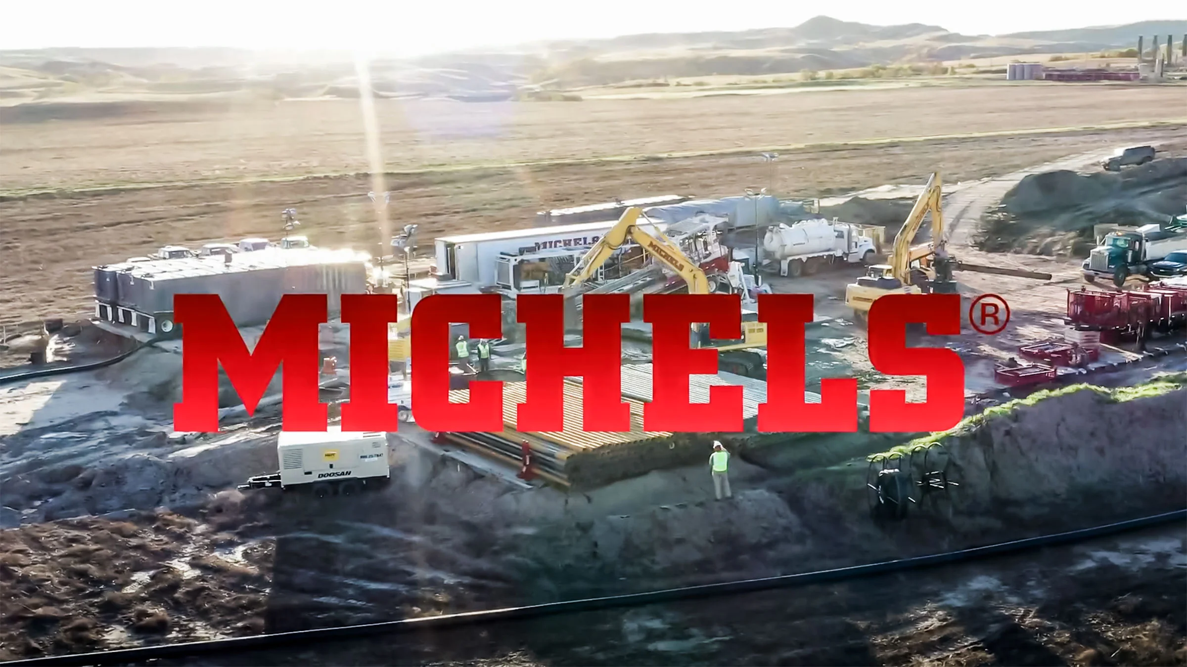 A brilliant sun rises over a Michels Trenchless jobsite, featuring the Michels logo.
