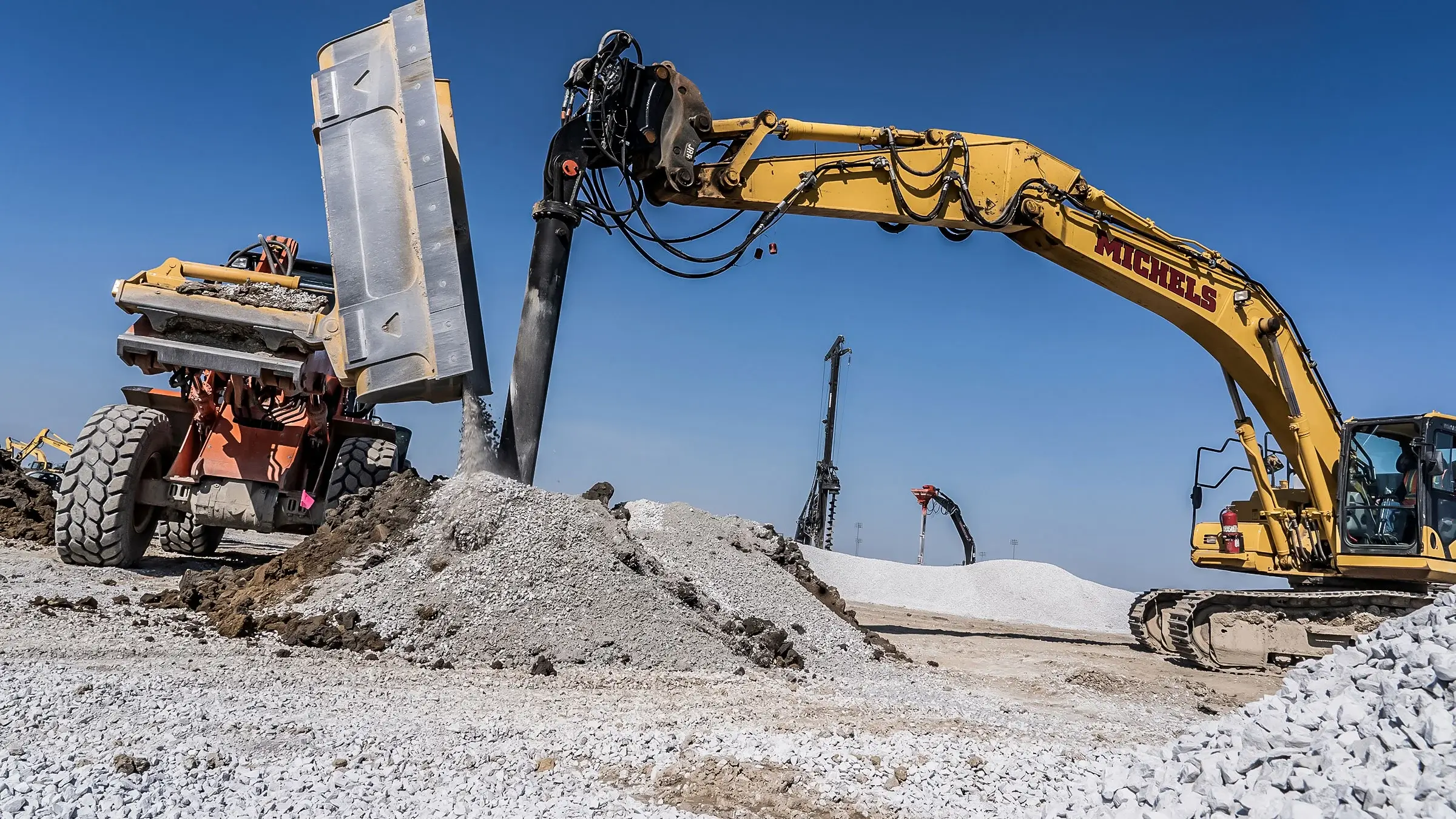 An excavator and backhoe assist in the installation of a ground improvement foundations job
