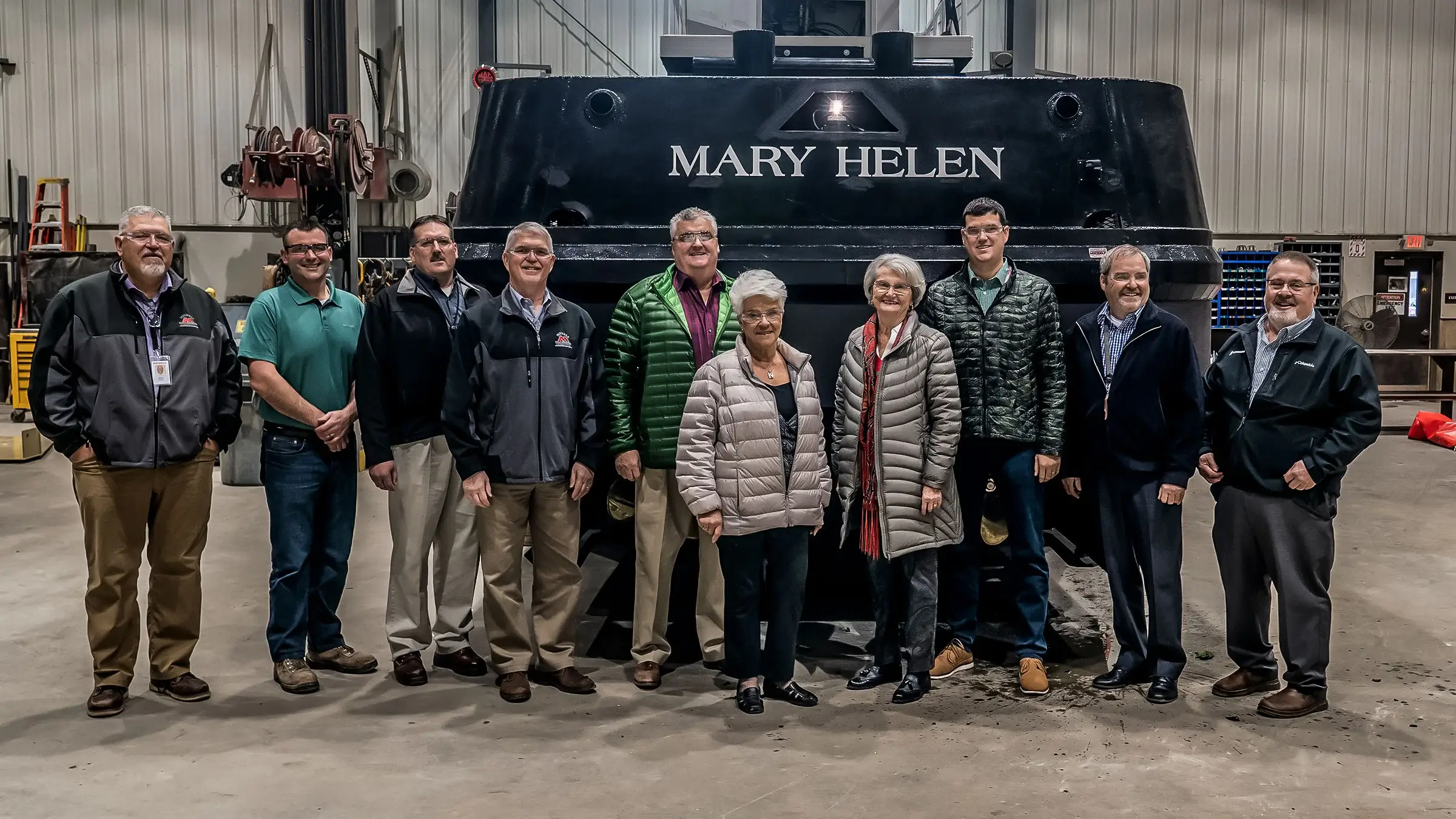 The Michels family and executives stand in front of the Mary Helen tugboat.