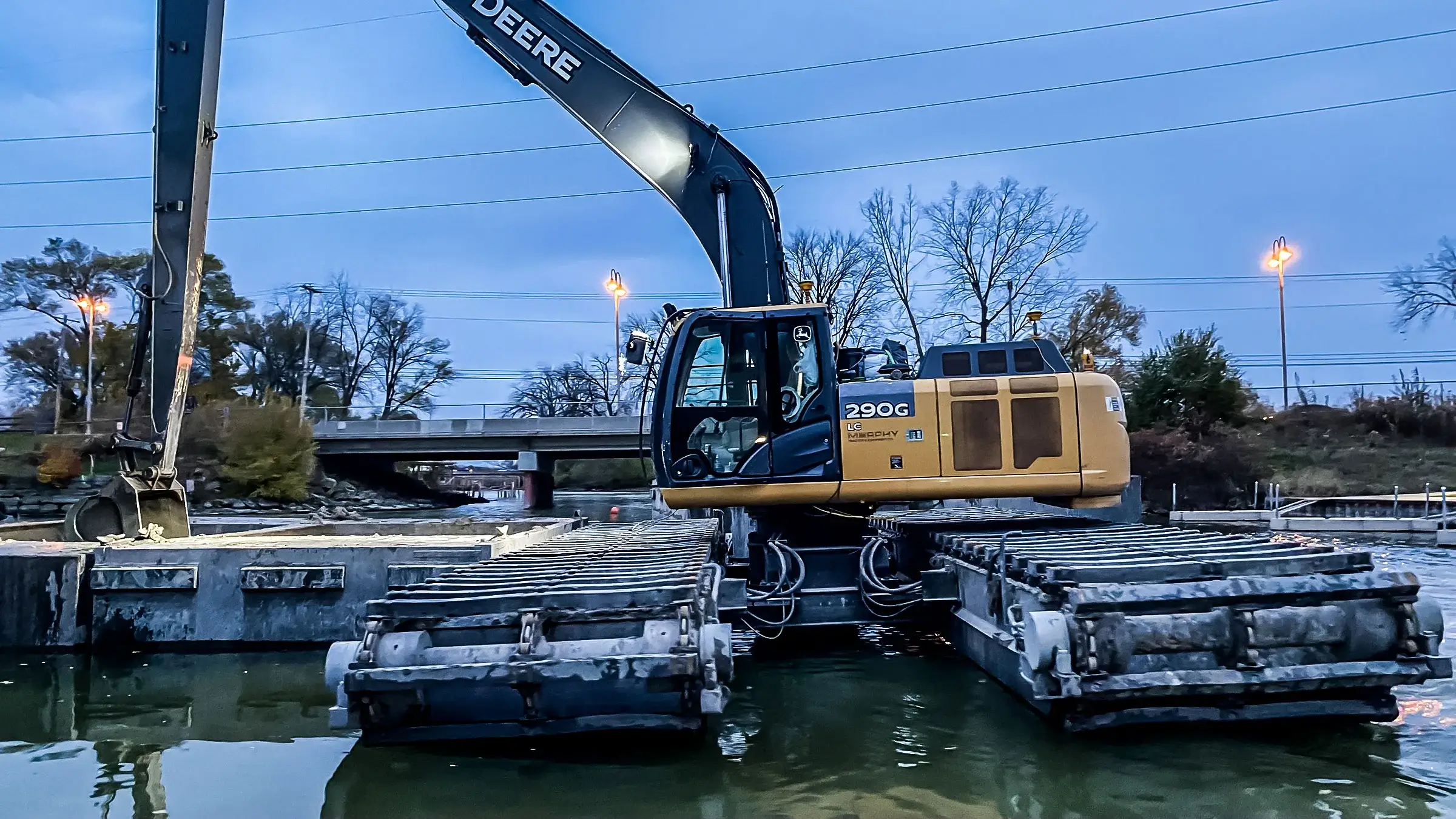An amphibious excavator loads a container with dregding material