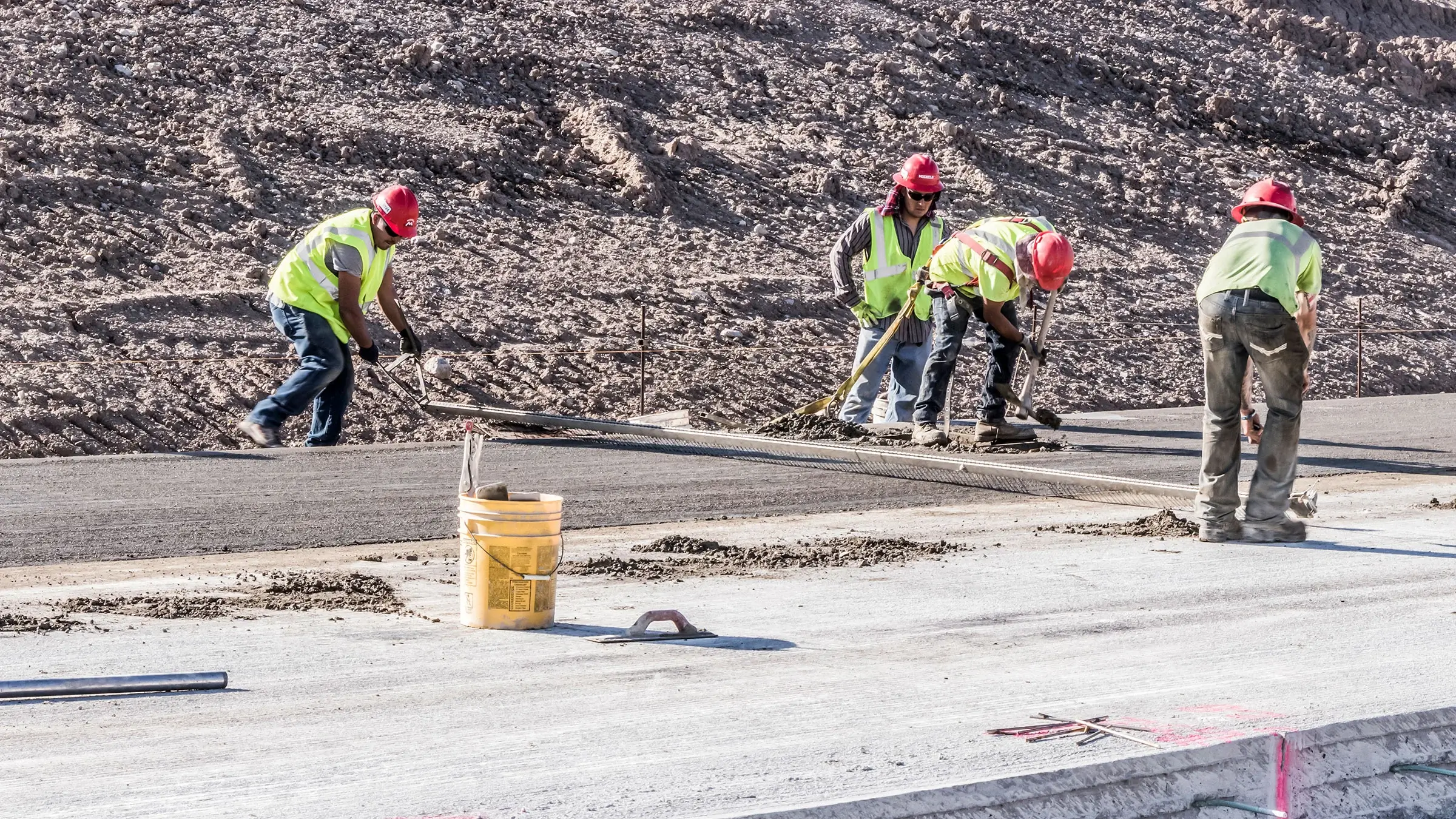 Several Michels crew members work to smooth concrete on a roadway