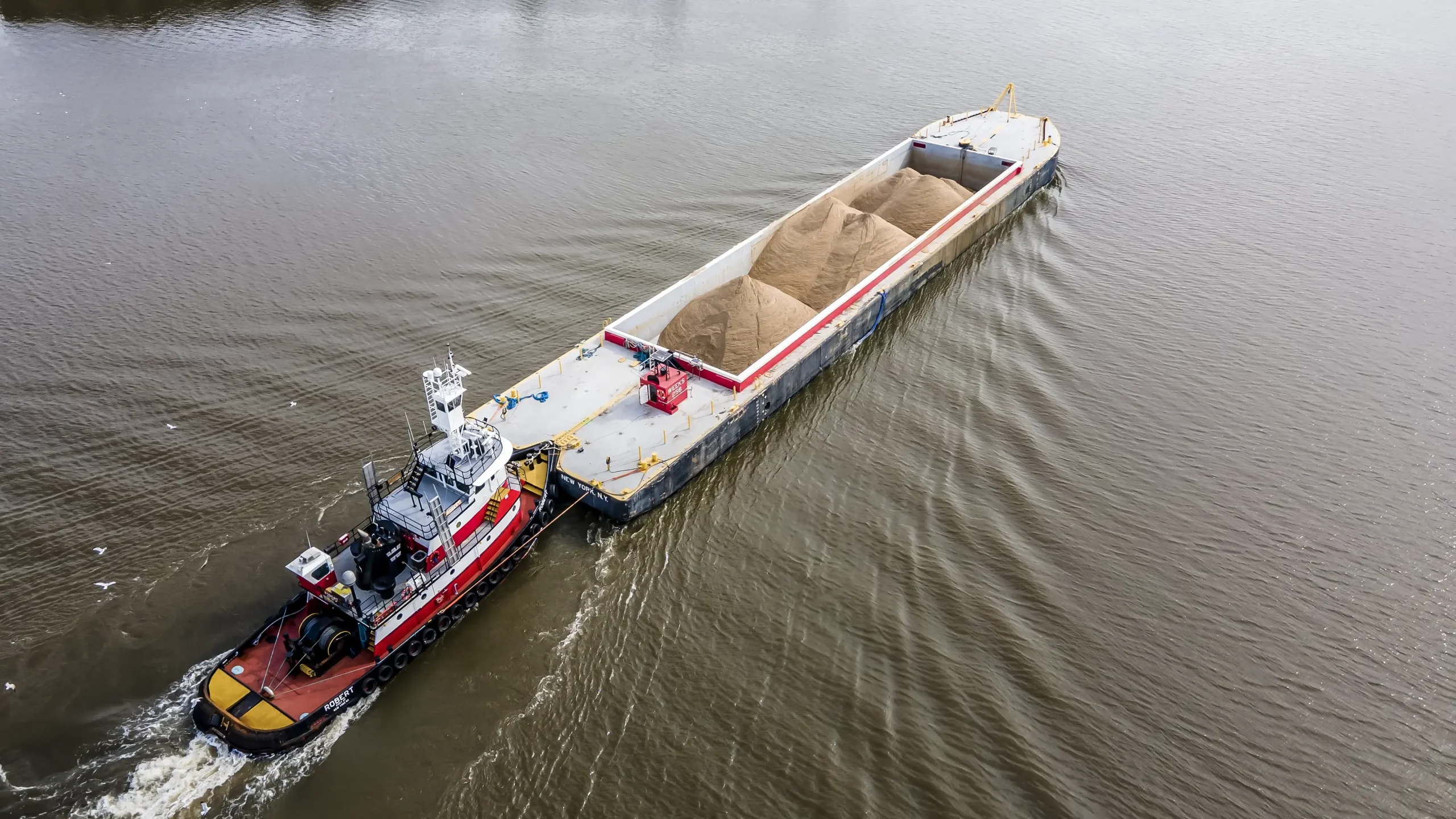 Boat moving sand aggregate over a body of water