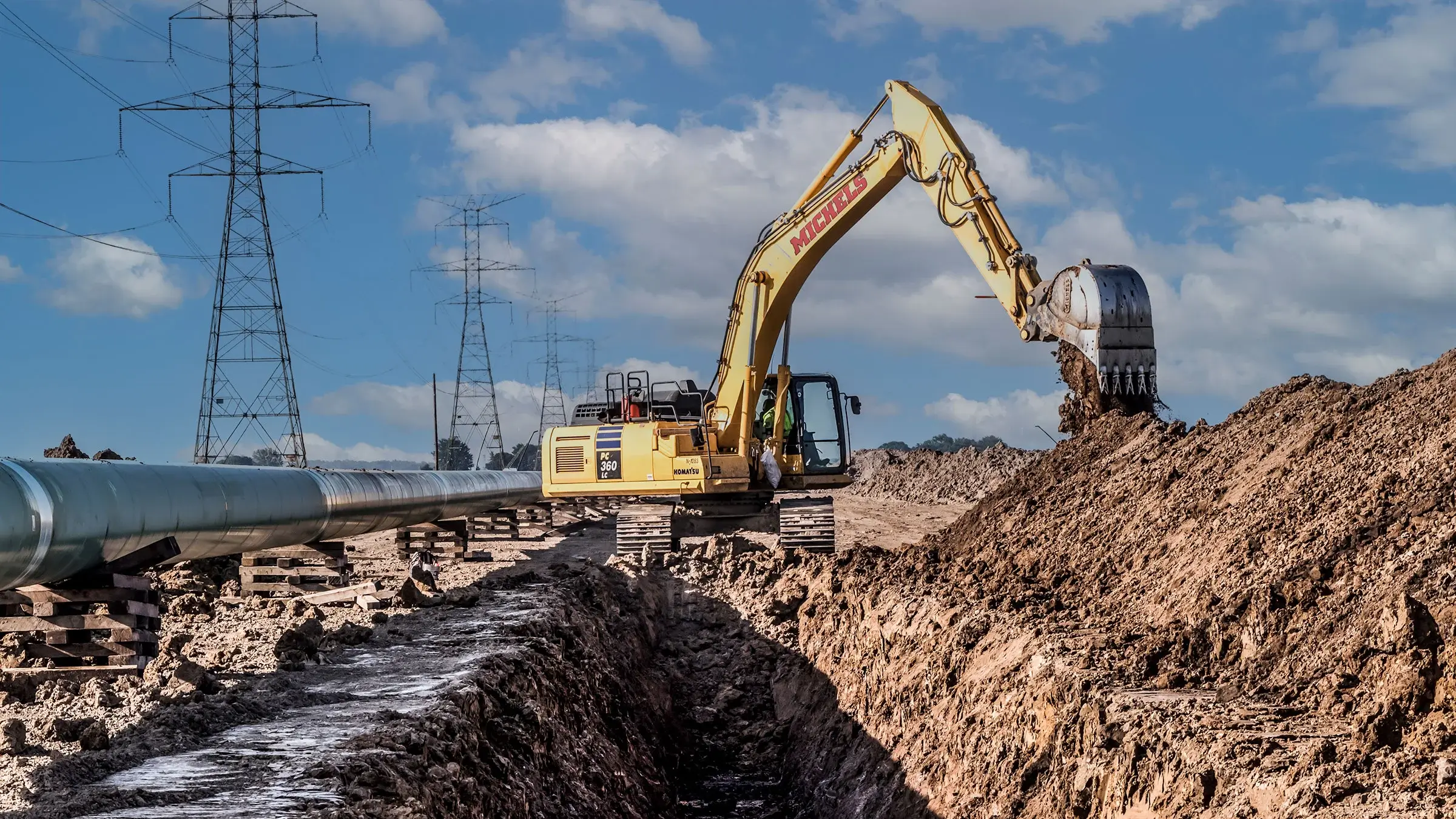 An excavator digs a large trench to fit a pipeline.