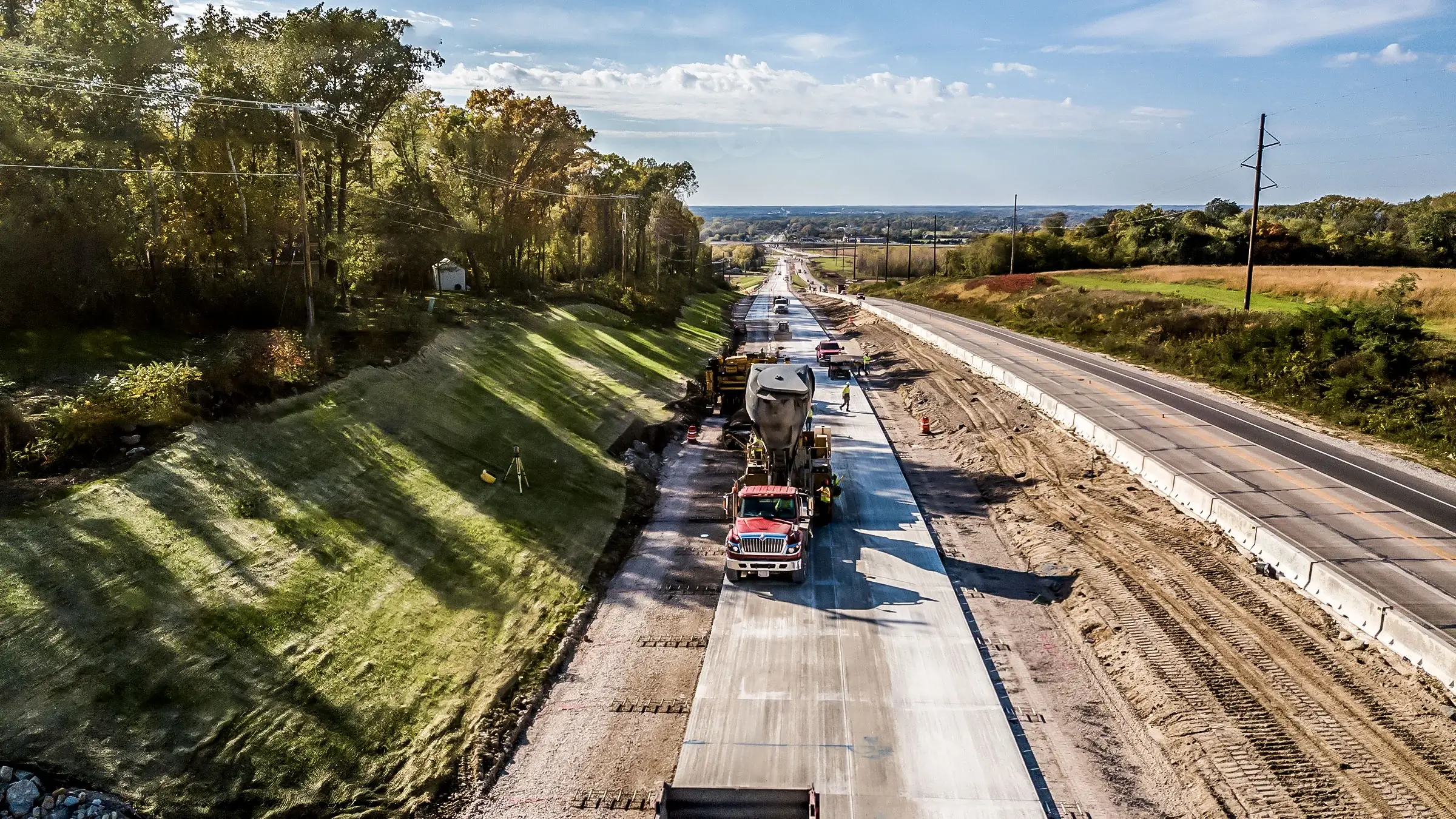 A paving jobsite stretches along a long highway.