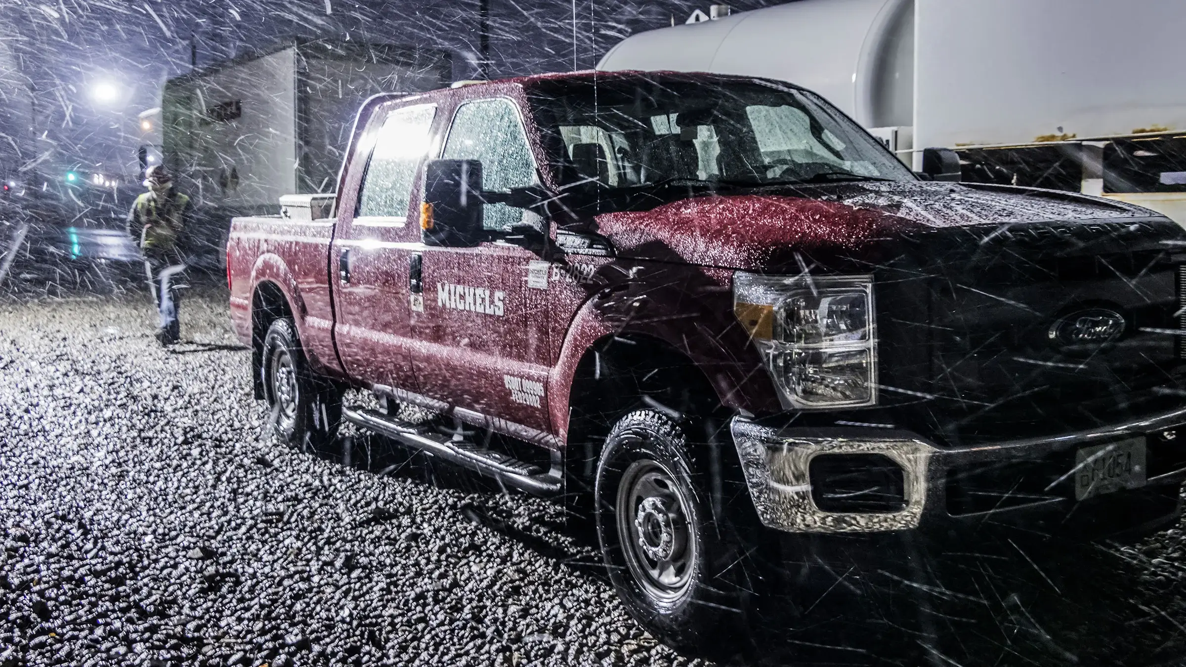 A pickup truck is parked on a construction site during a snowstorm
