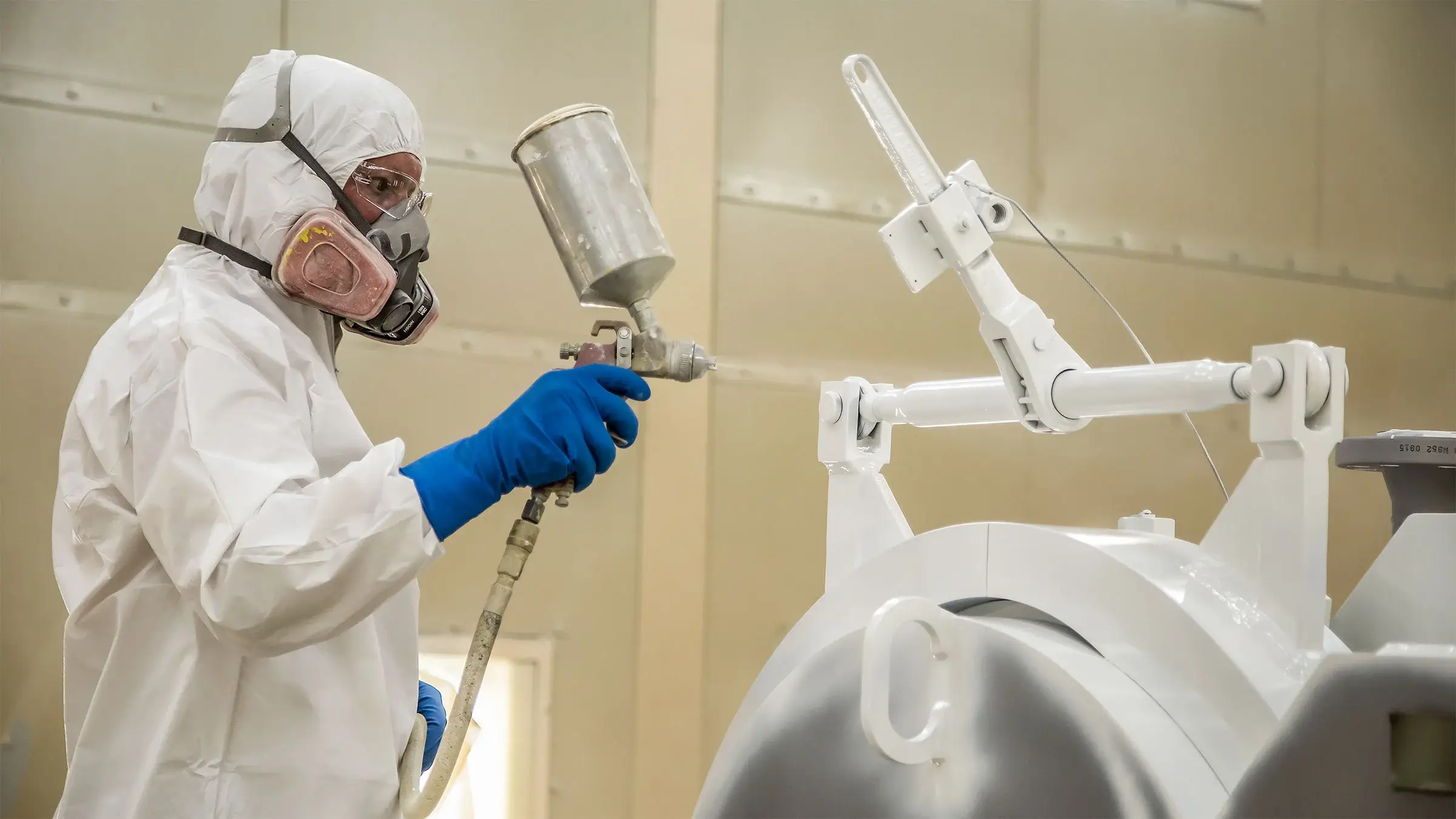 A painter uses a spray gun to coat a fabricated pipe at CFS facilities in Carrollton, MO