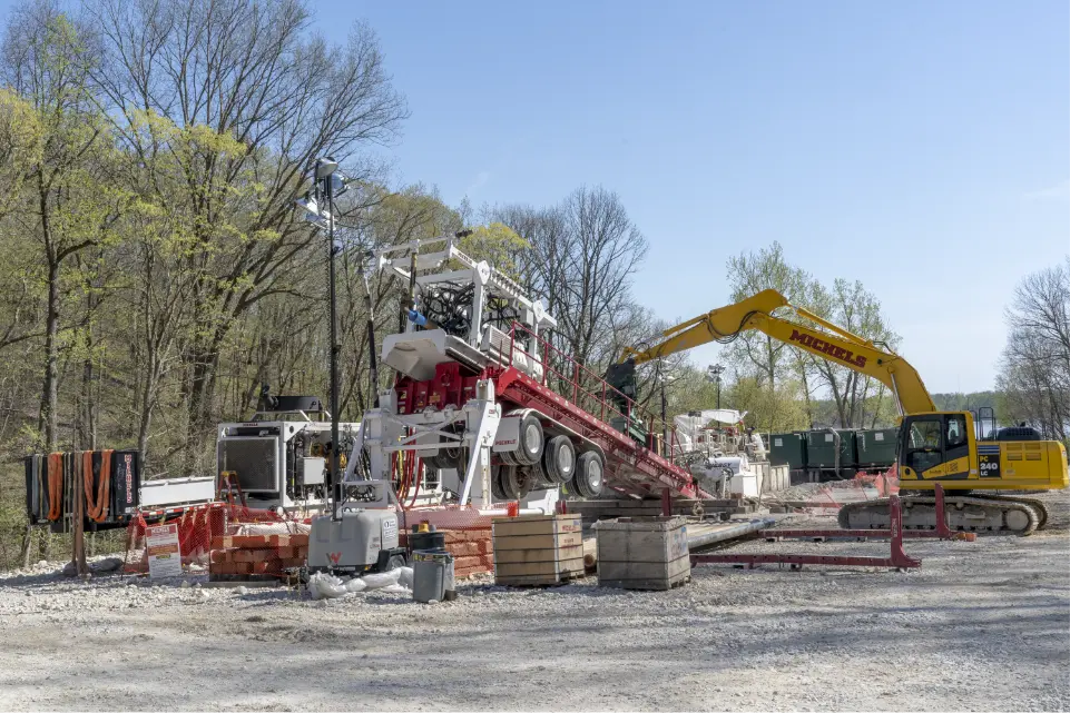 An excavator and HDD drill rig operate on a jobsite.