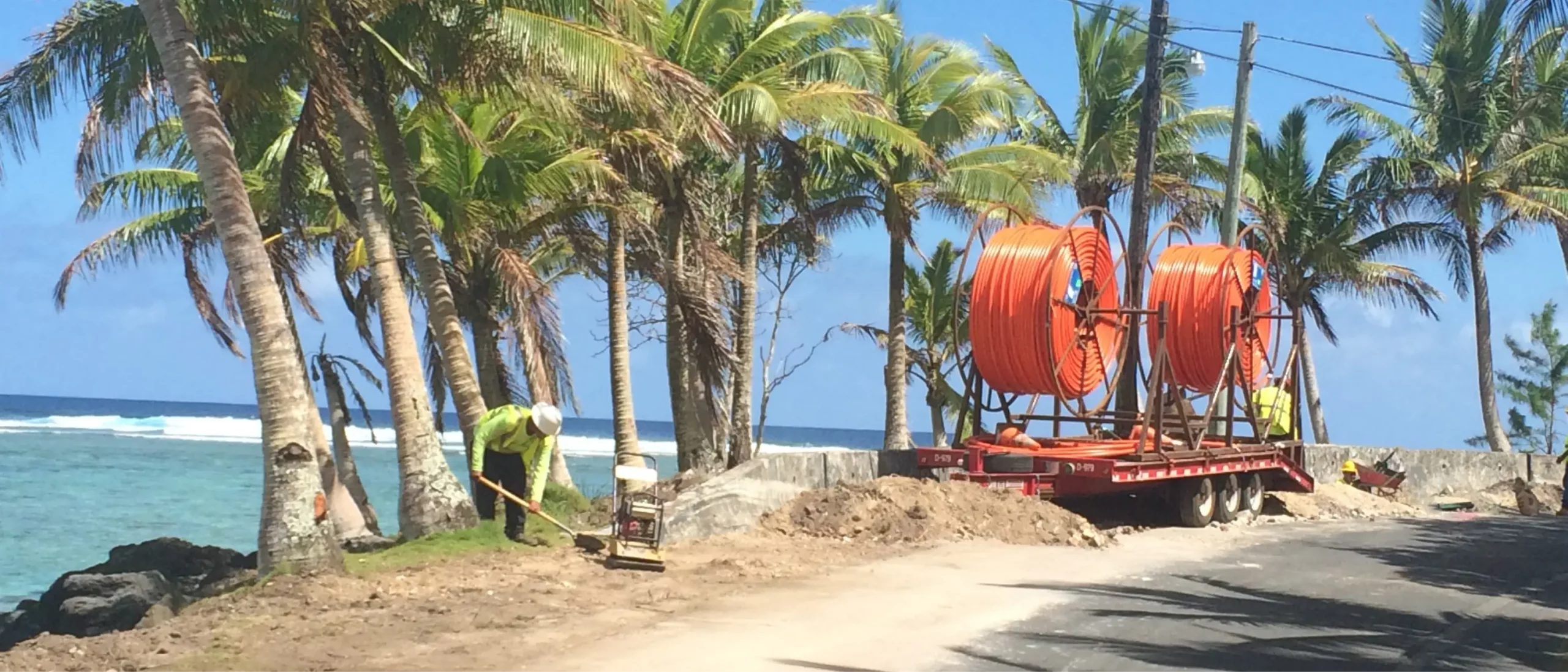 A Michels crew member working near the ocean and palm trees in Guam