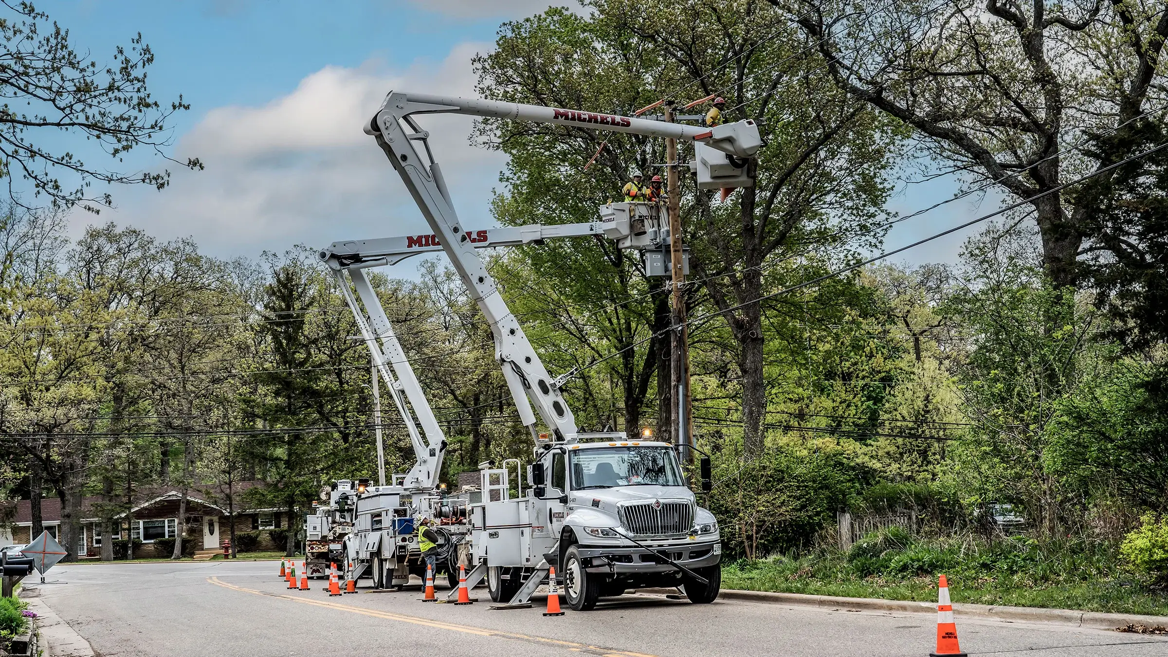 A crew works on a power line from bucket trucks