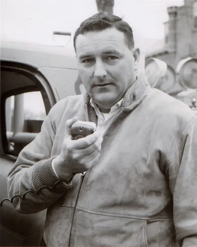 Black and white headshot of Dale Michels holding a communication device