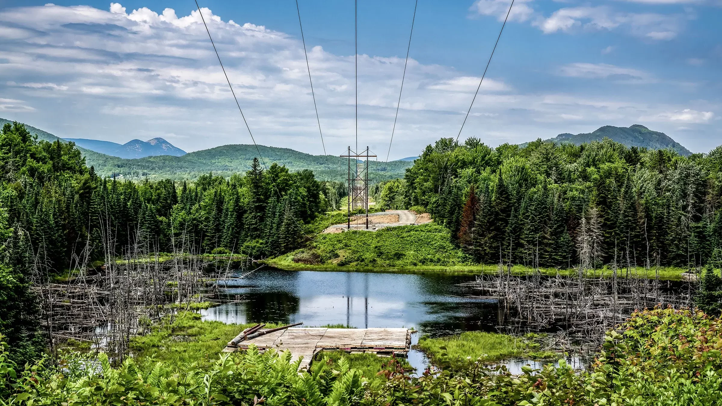 A transmission power line project over water, trees, and mountains.