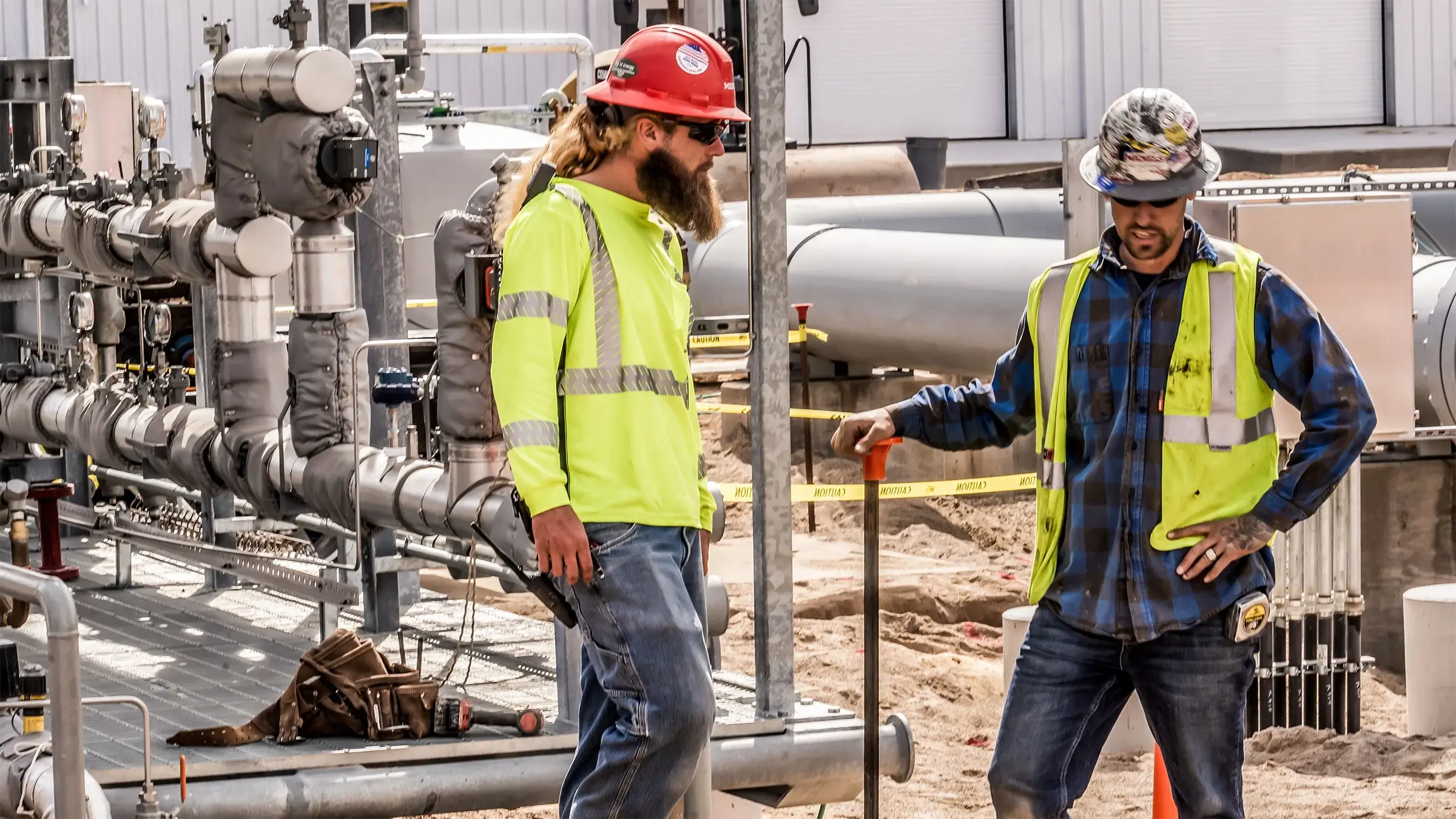 Two people talk onsite of a natural gas compressor station