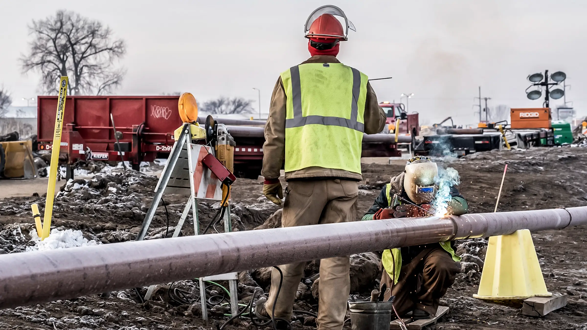 A welder connects two joints of gas distribution pipeline