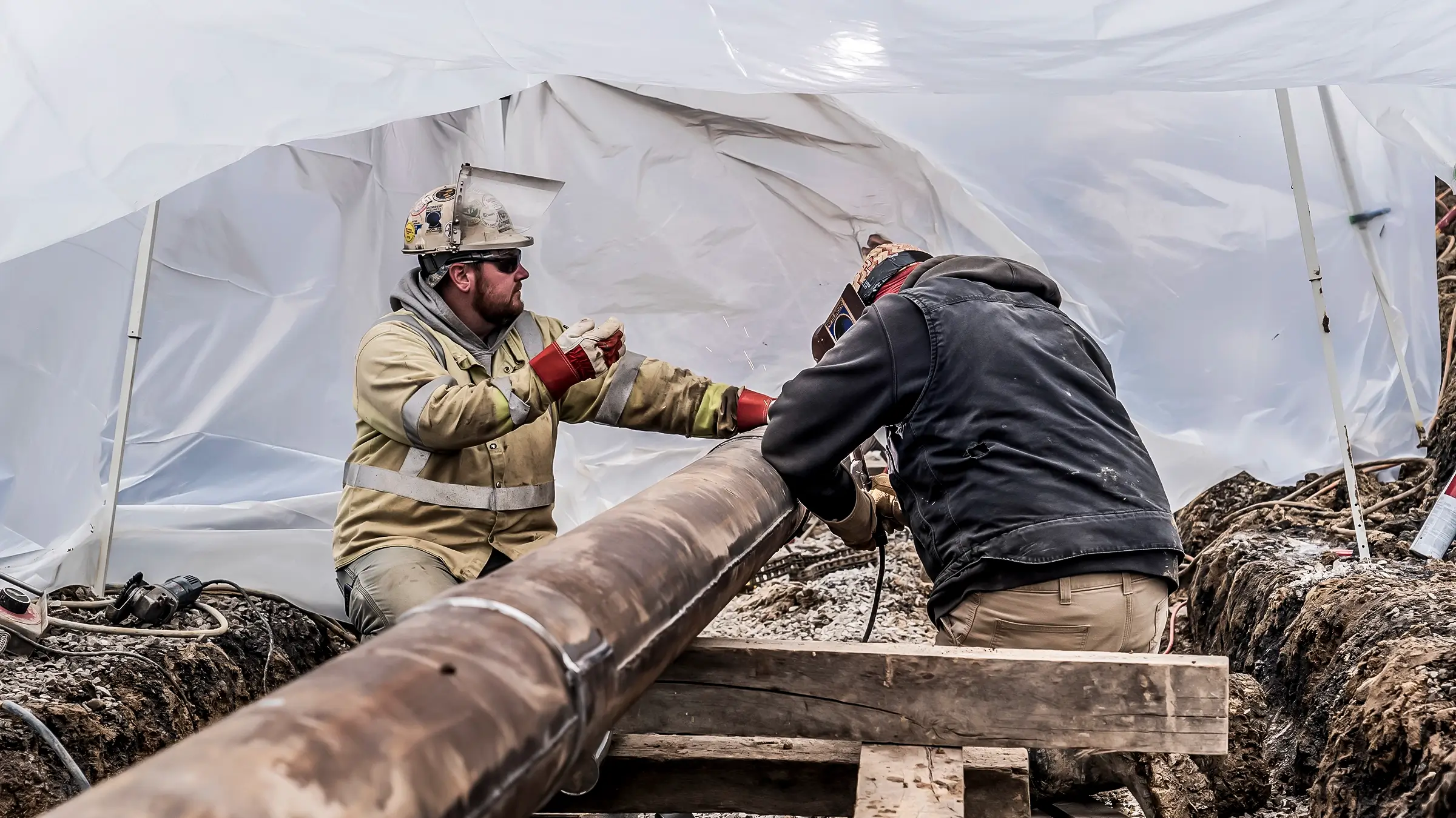 Two welders work on a sleeve installation job on a small diameter pipeline.