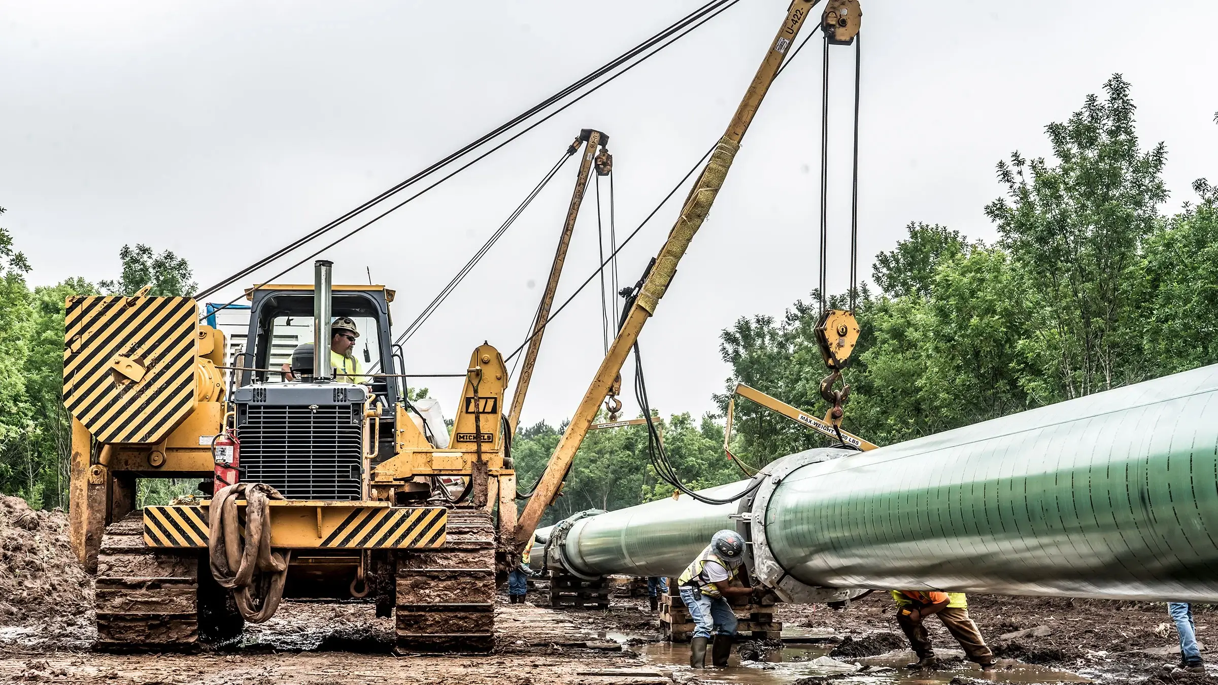A pipelayer works along side other crew members in preparing a pipeline