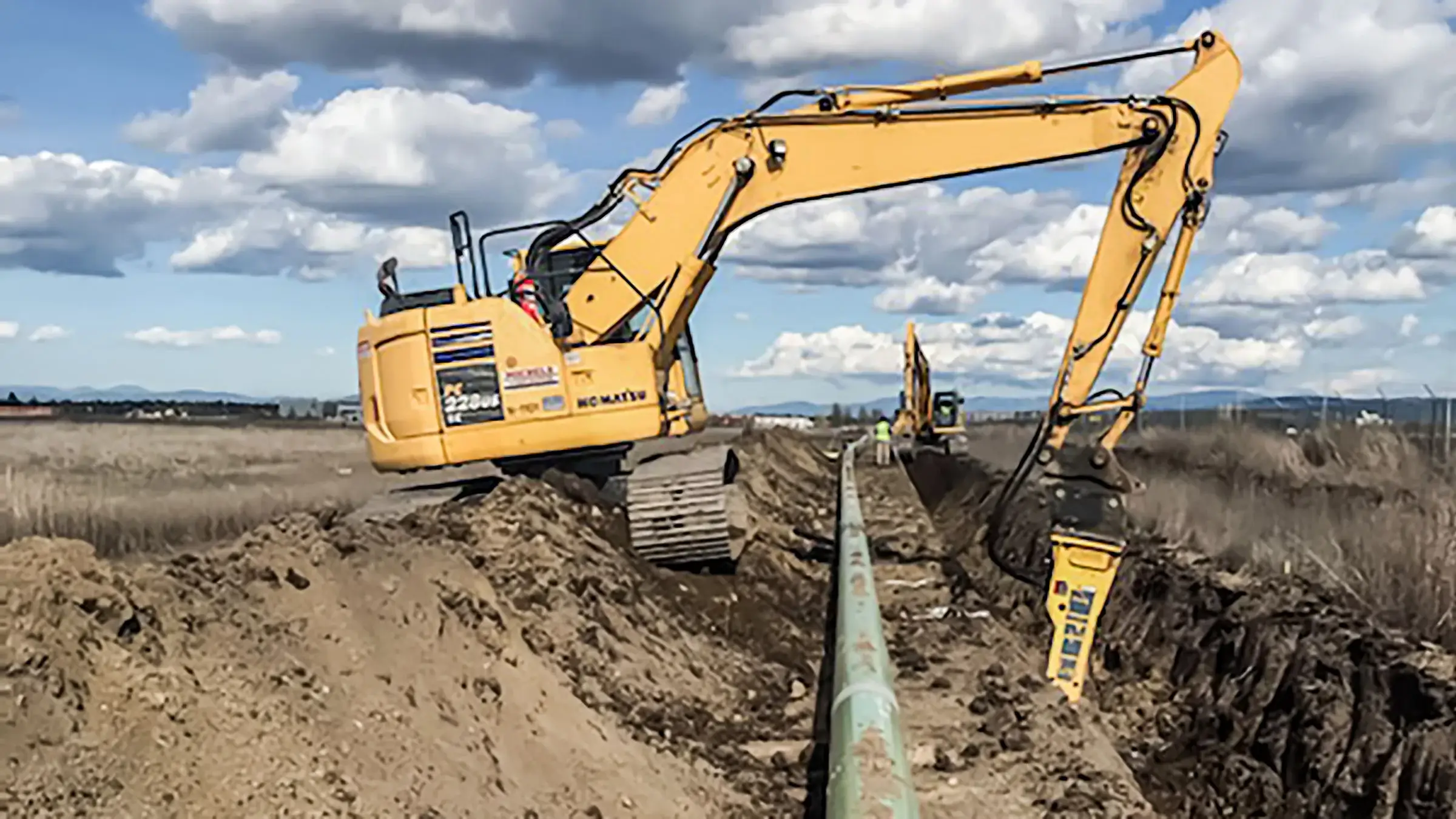 Several excavators assist in digging out a trench for a pipeline to be placed