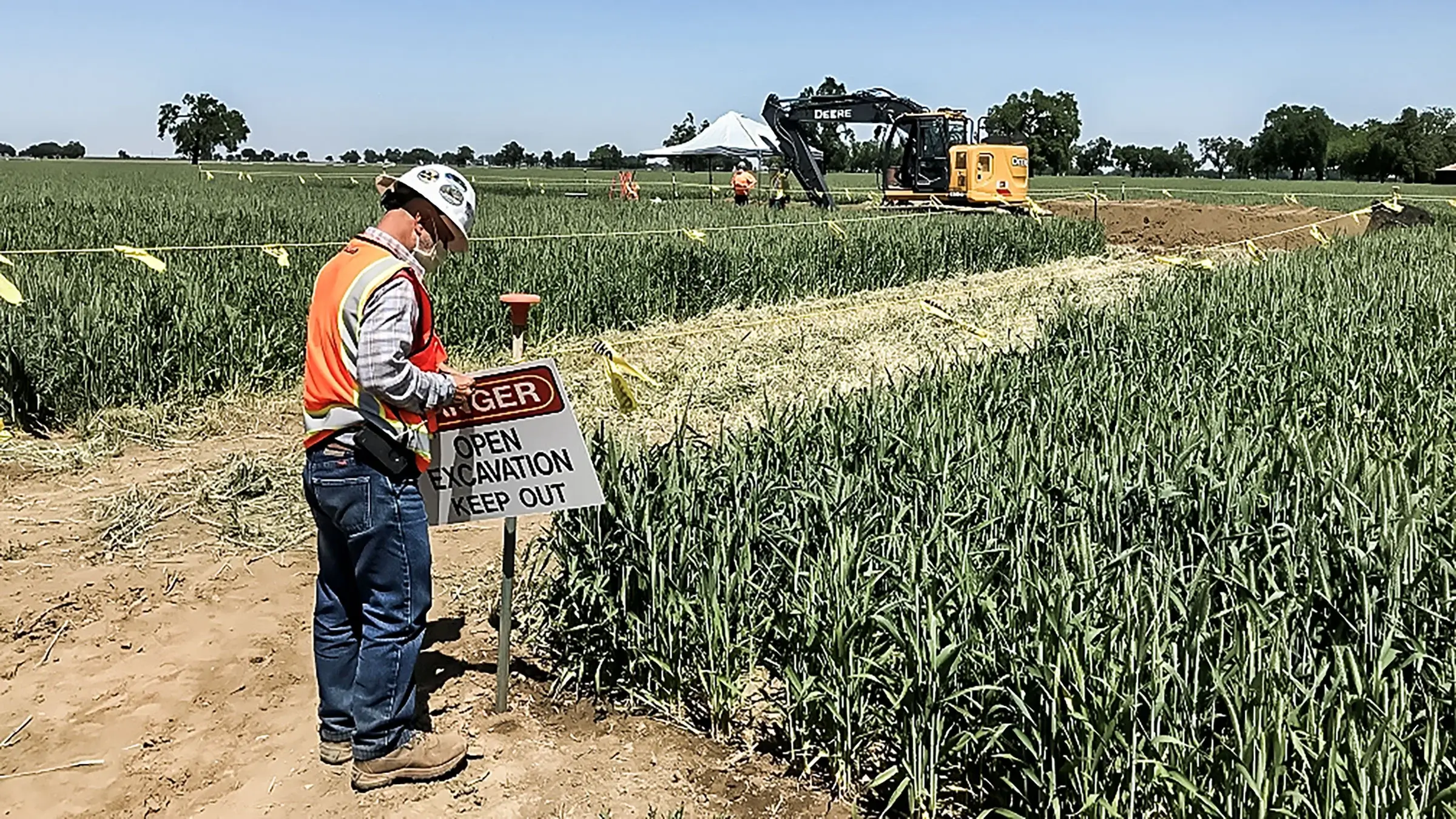 A Michels crew member posts up a Danger sign near a farm land excvation project