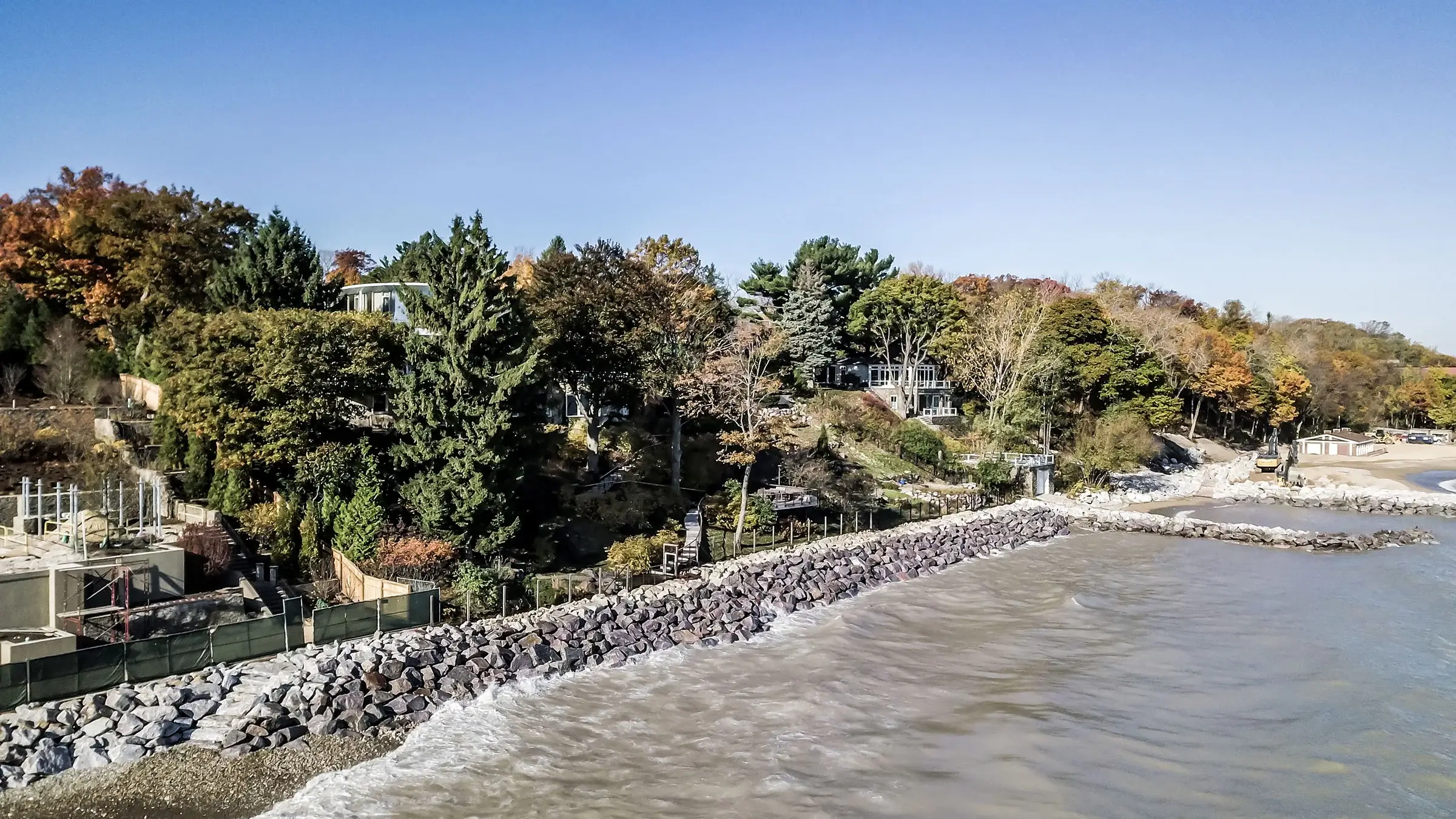 A revetment wall consisting on large stones sits along a shoreline near homes.